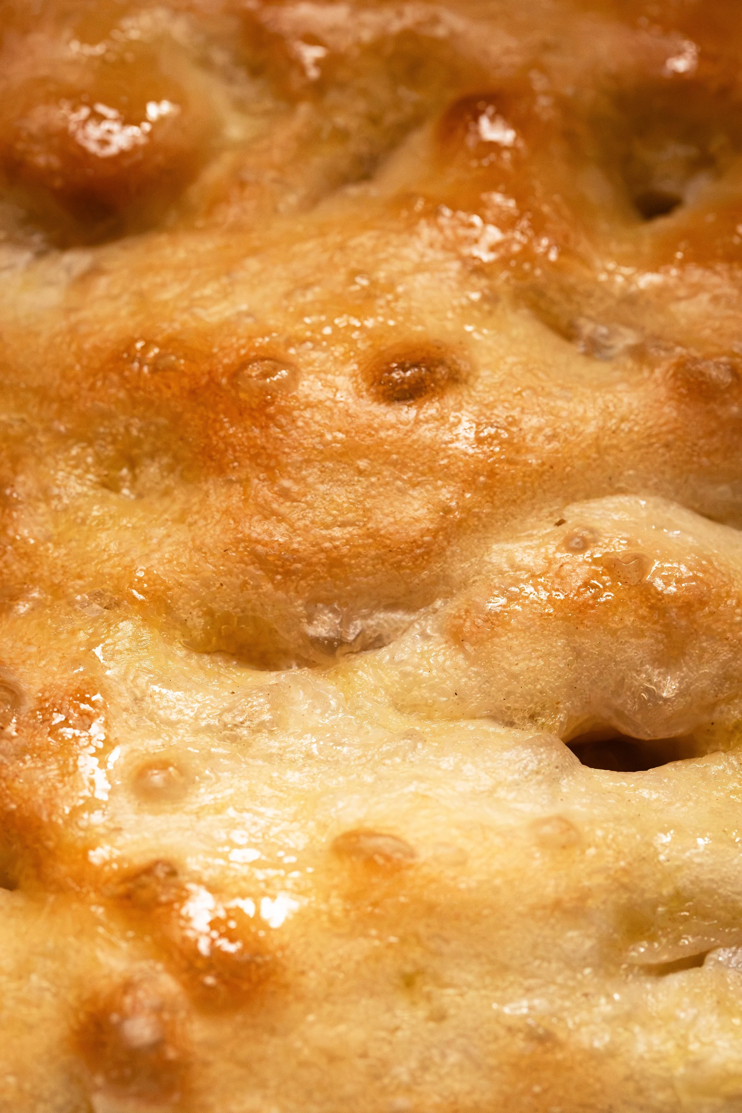 Close-up of a cheesy baked dish with browned cheese and bubbling melted cheese on top.