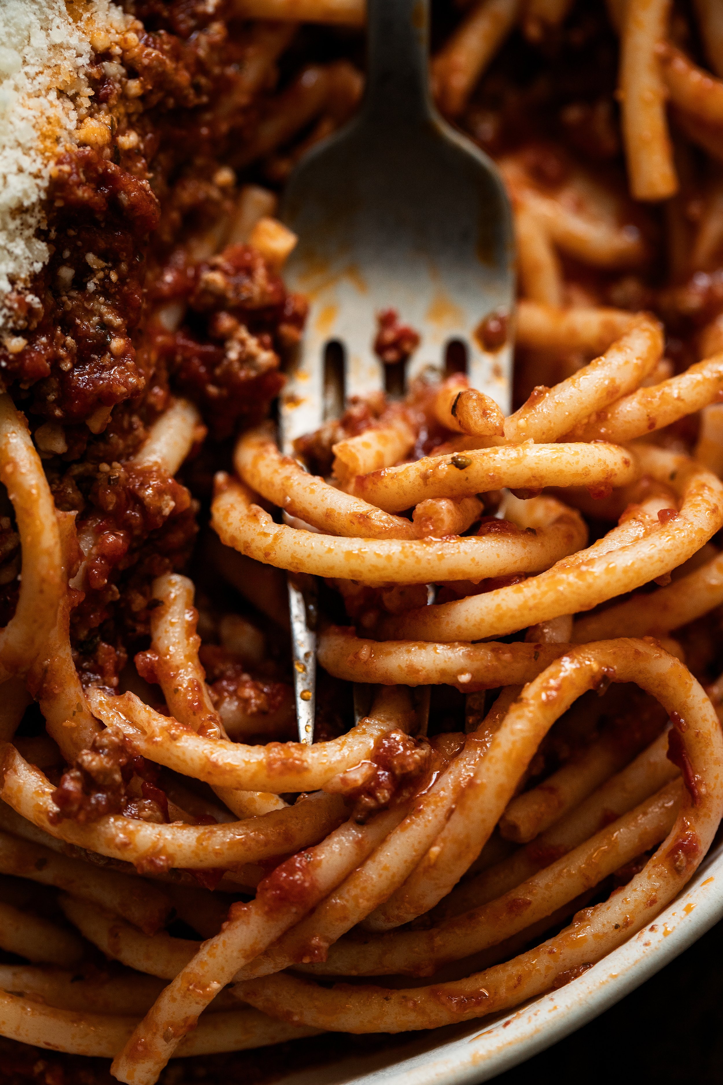 Close-up of spaghetti with meat sauce and grated cheese, served in a bowl.