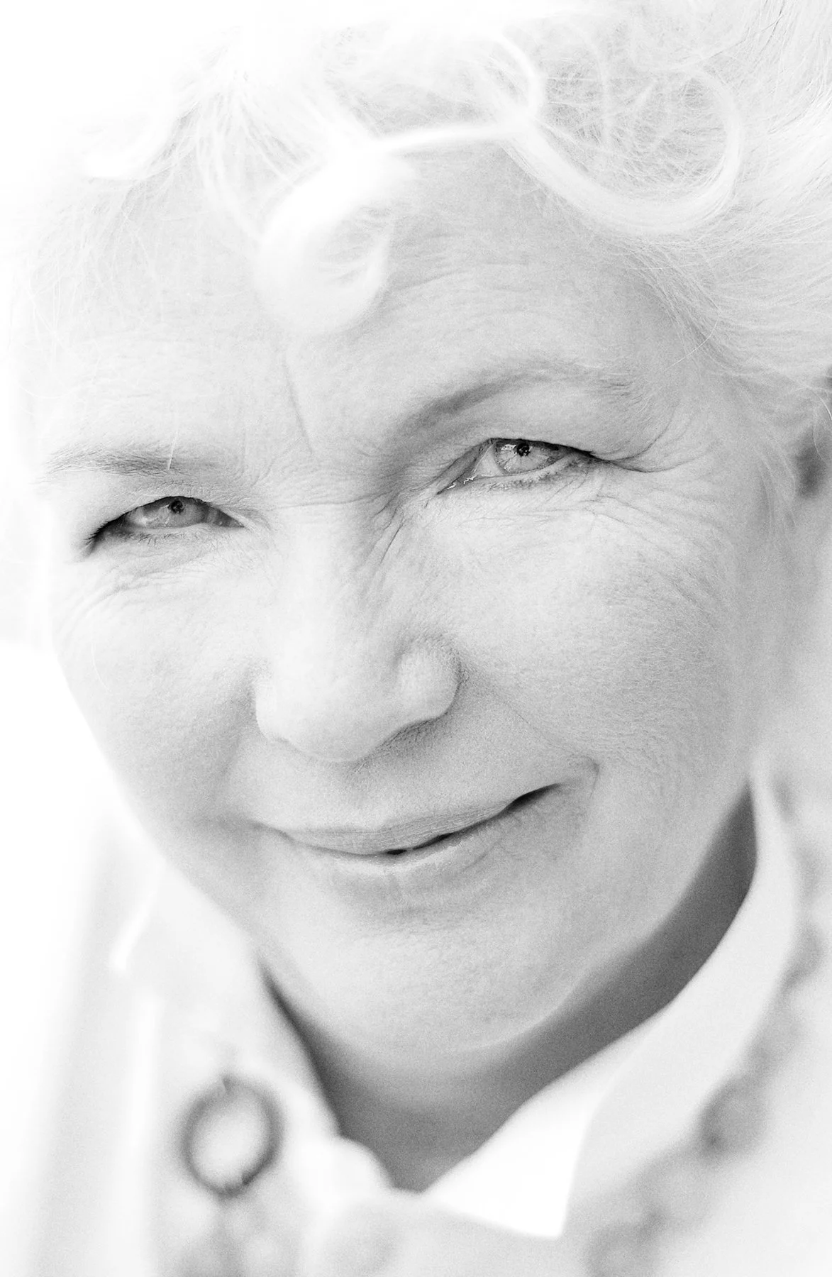 Close-up black and white photo of a smiling woman with light-colored hair, partially closed eyes, and a big smile showing her teeth.