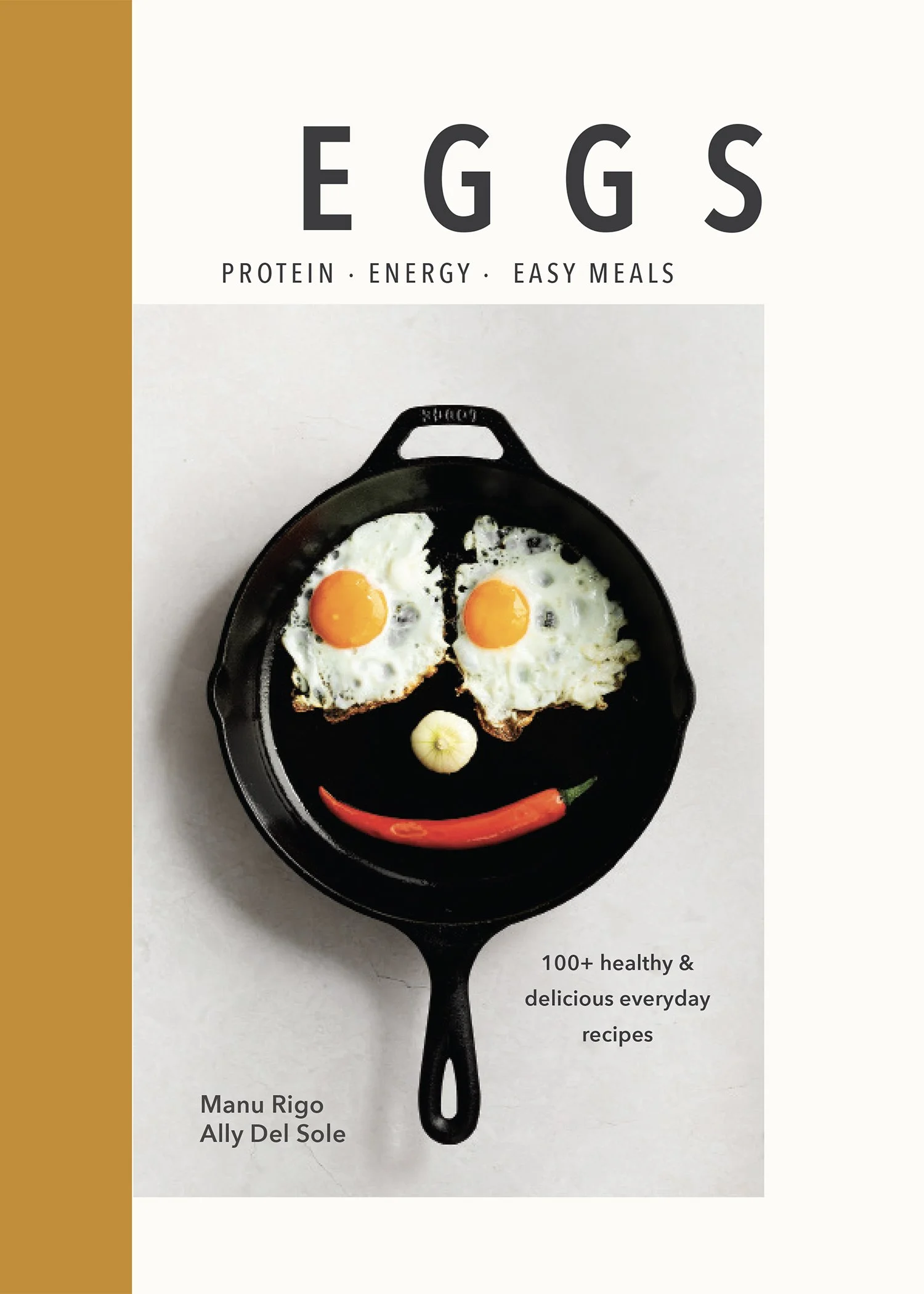 A cookbook cover titled "Eggs" with a subtitle "Protein, Energy, Easy Meals". The cover features a skillet with two sunny side up eggs arranged to form a face, with a garlic clove as a nose, a red chili pepper as a mouth, and an onion as a chin. The authors listed are Manu Rigo, Aly Del Sole, and another. The partial text indicates the book contains 100+ healthy and delicious everyday recipes.