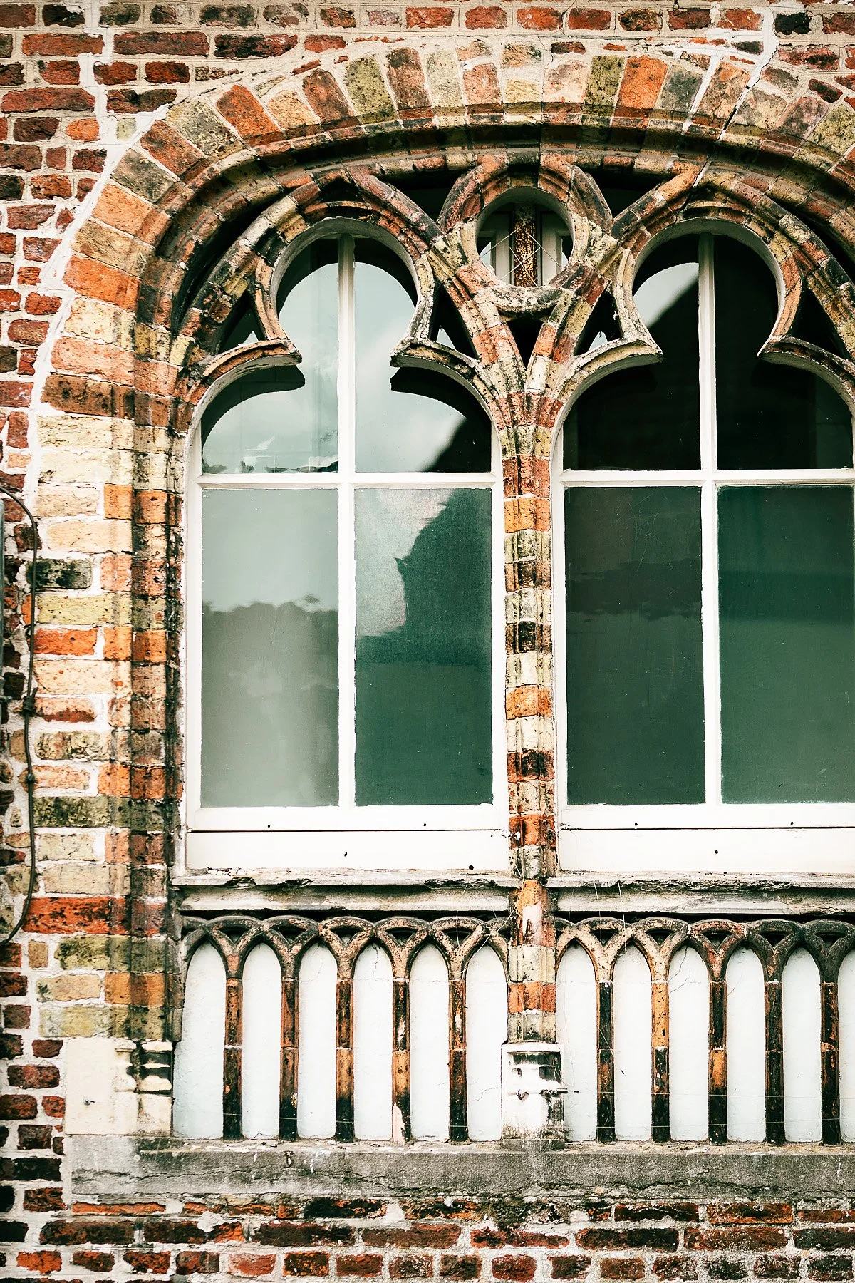 Close-up of an old brick building with Gothic-style arched windows and decorative brickwork.