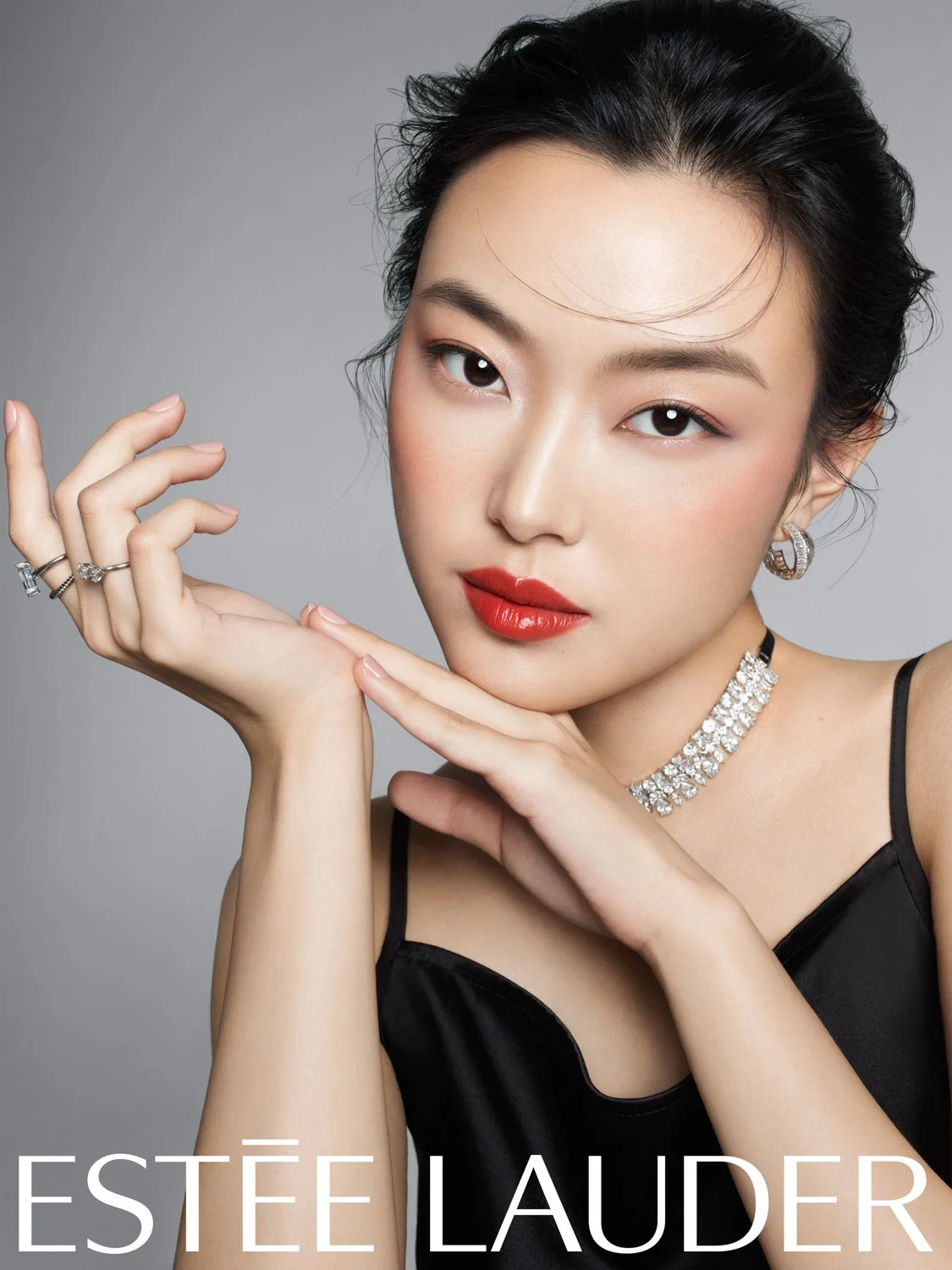 Beauty portrait of model with natural skin and red lip, wearing diamond jewelry, Estée Lauder campaign photographed by Stockton Johnson