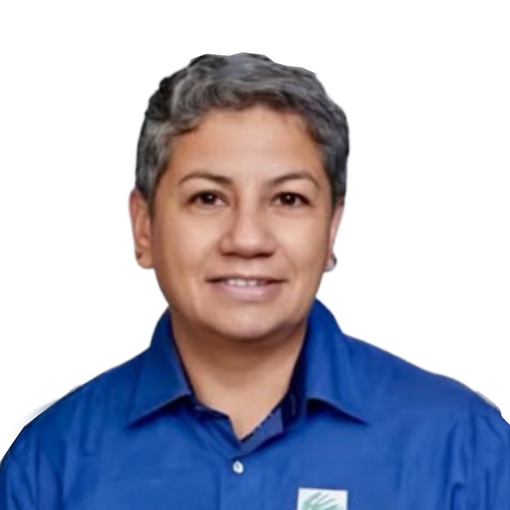 Mujer con gafas grandes, sonrisa, cabello rubio, usa aretes pequeños y collar, lleva ropa azul y un gafete de identificación