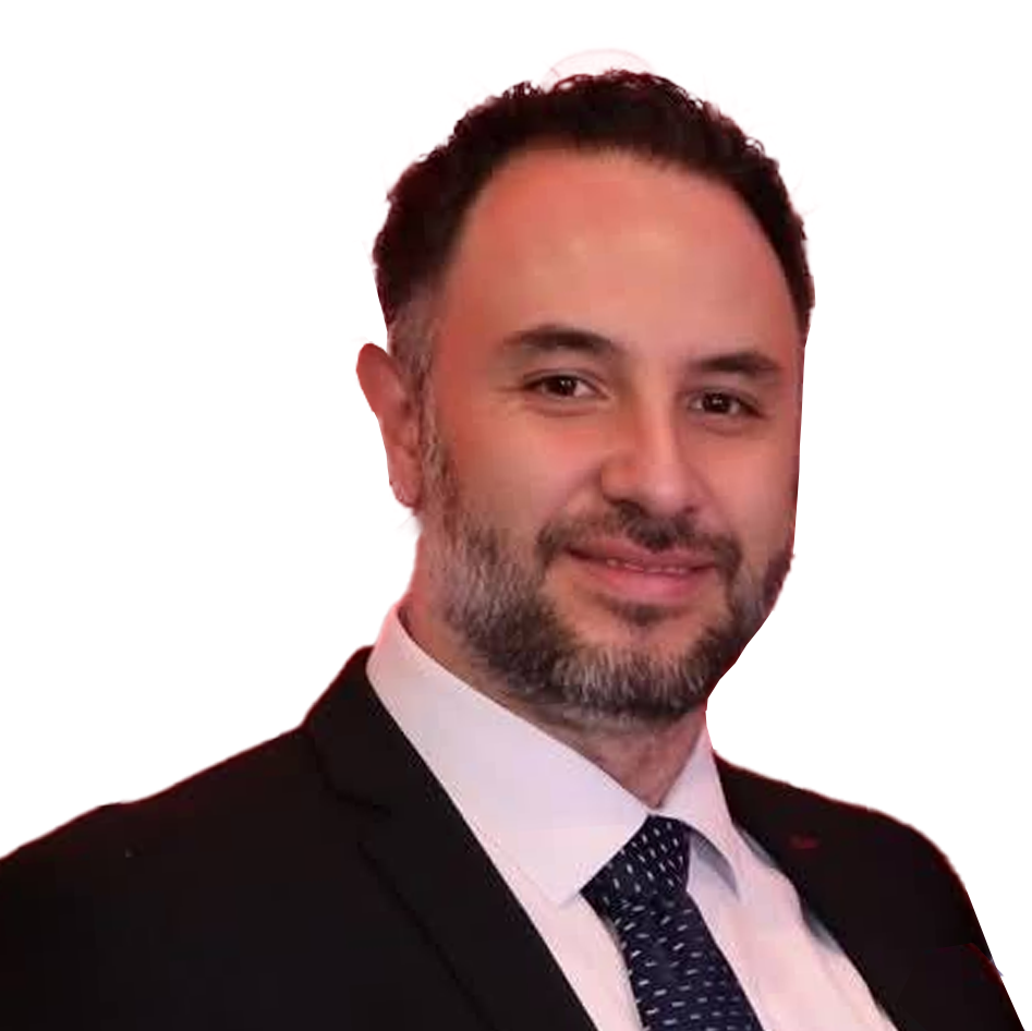 Retrato de un hombre con barba, vendiendo traje negro, camisa blanca y corbata azul con puntos blancos, en un fondo blanco.