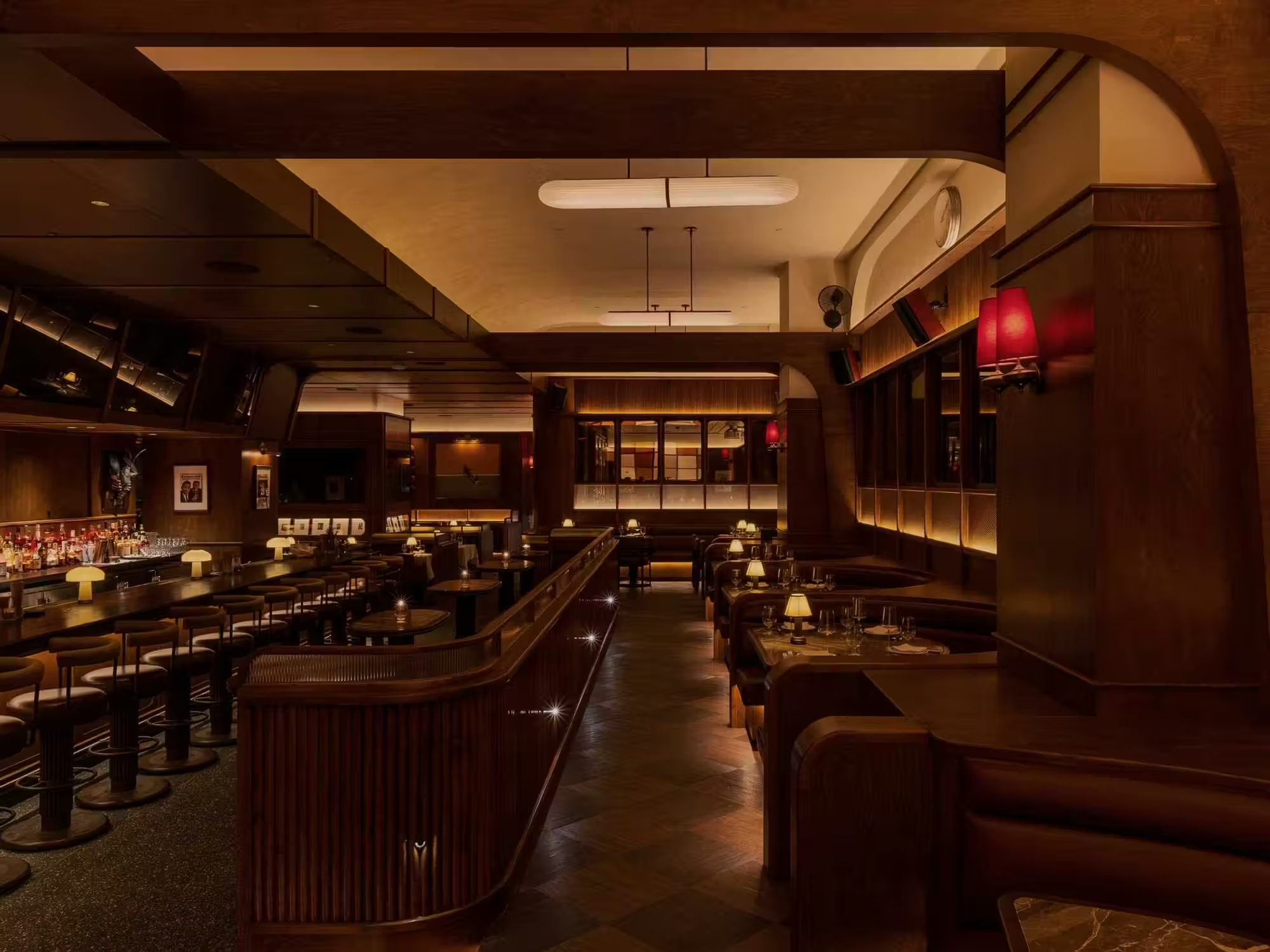 Finished interior of Austin Sports Club in downtown Austin, designed by PETERMAX Co. with dark wood millwork, integrated sports displays, intimate booths and warm layered lighting.