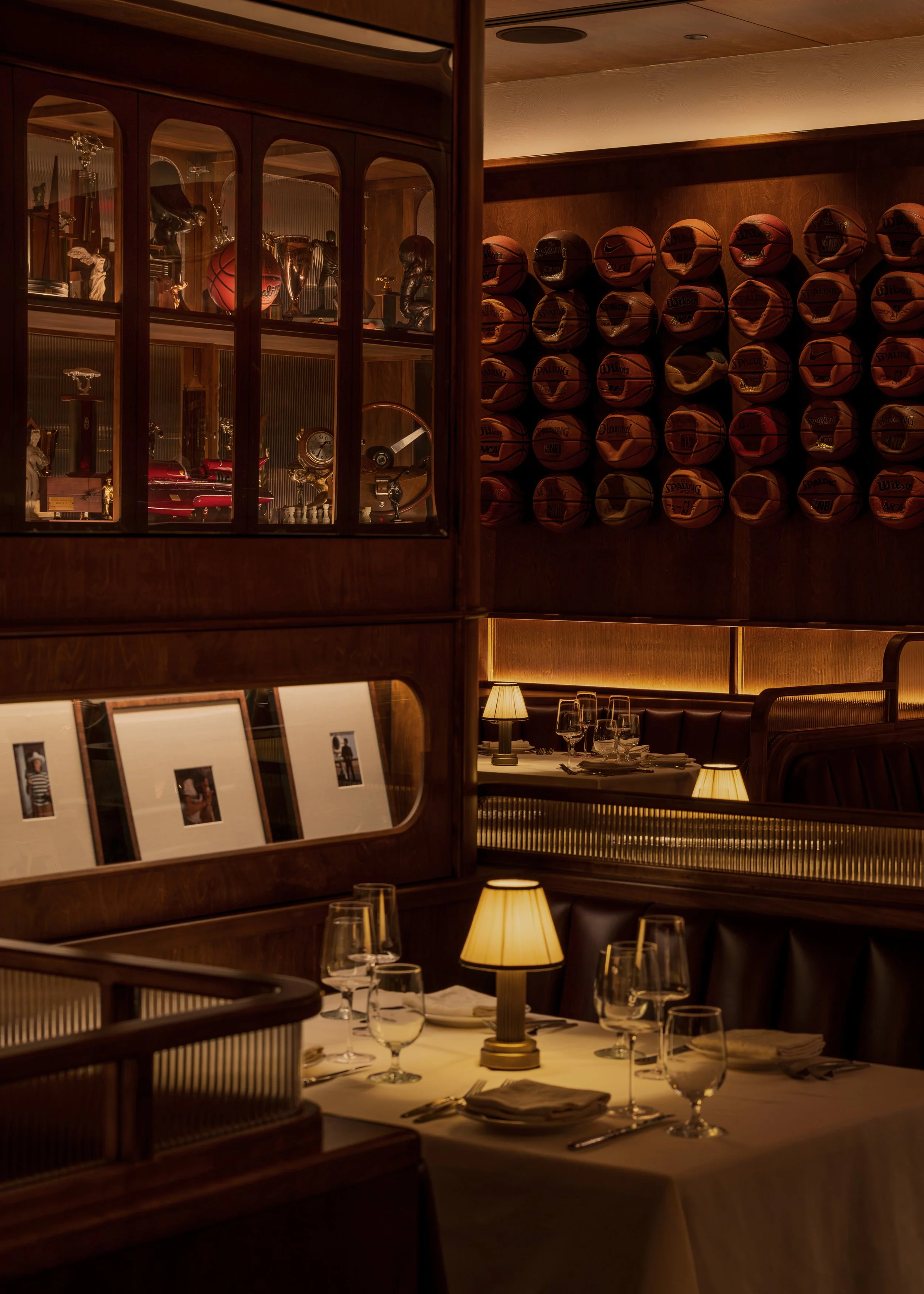 Historic sports photographs, illuminated display cabinets and the basketball feature wall surround an intimate leather banquette.
