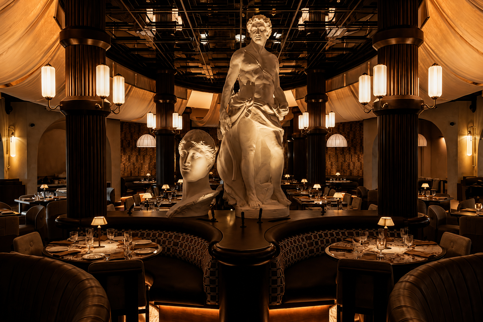 Interior of Roman God of Fire restaurant in Tempe, Arizona, with monumental classical statues, fluted columns, sculptural lighting, curved banquettes, and warm amber illumination.