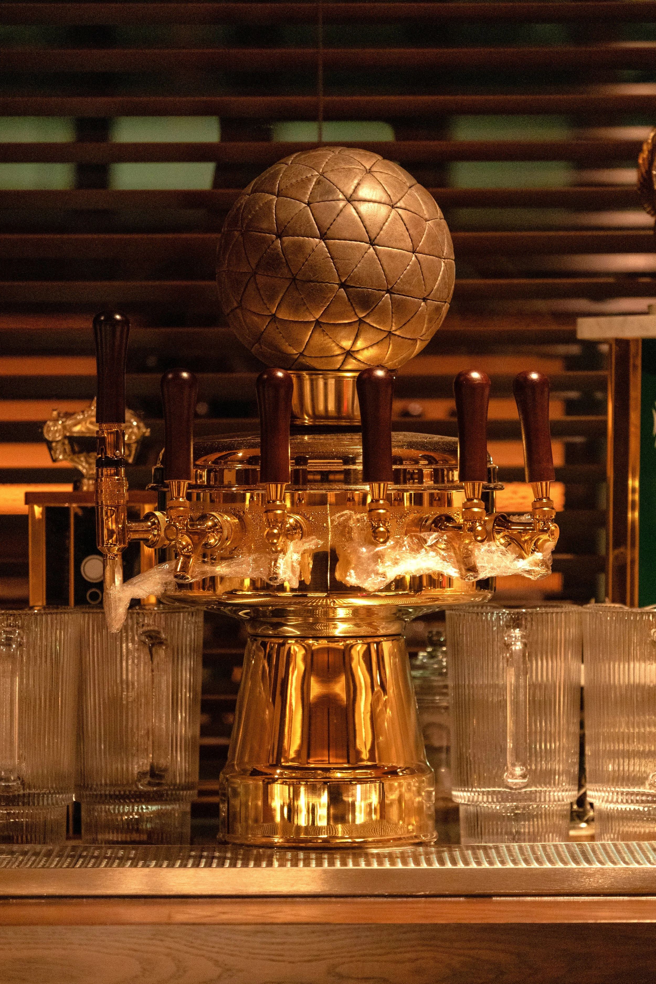 Custom brass tap tower topped with a vintage-inspired football inside Austin Sports Club, part of the downtown Austin interior designed by PETERMAX Co.