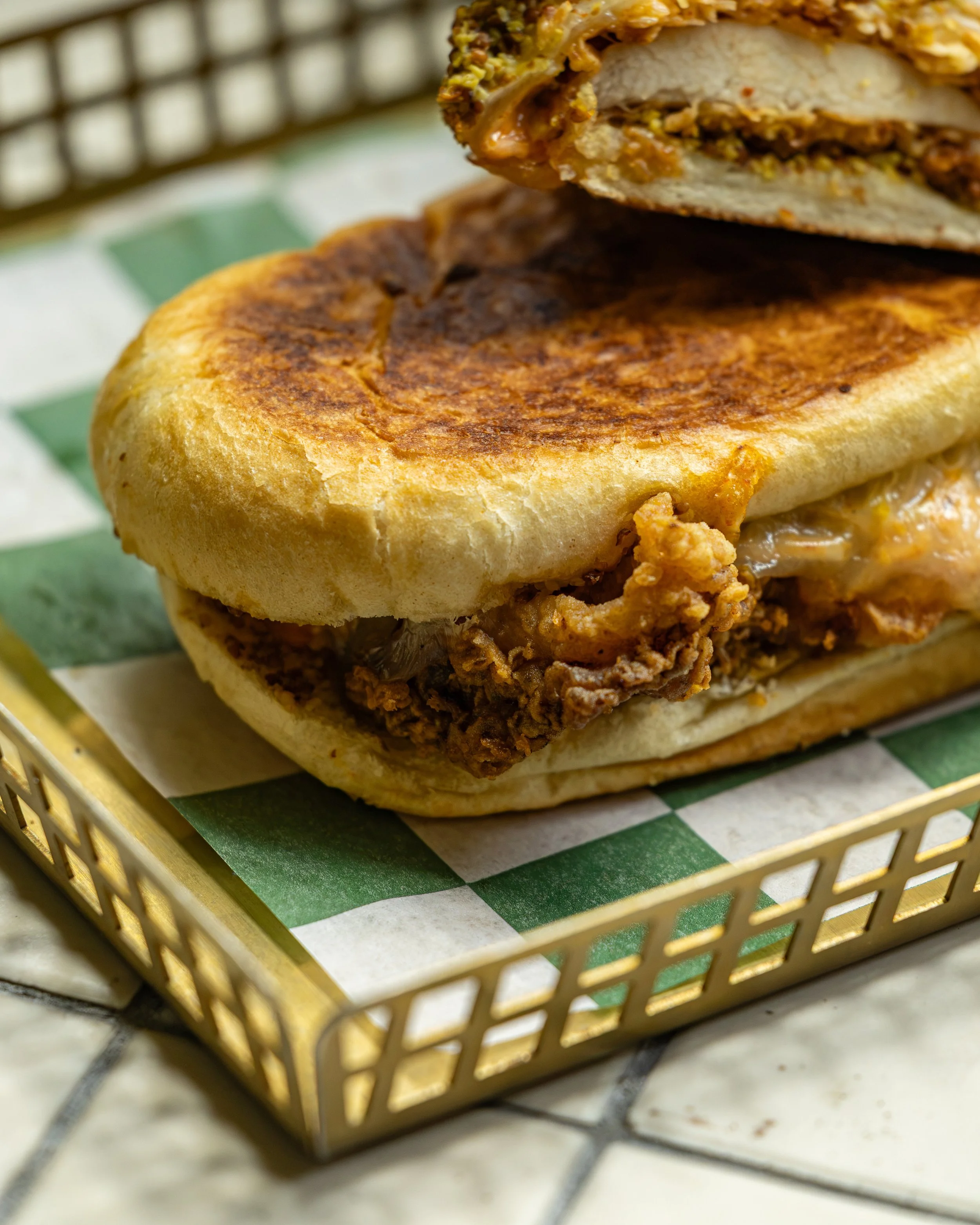 Griddled sandwich with protein and cheese, served in a checkered basket at Manny’s in Austin.