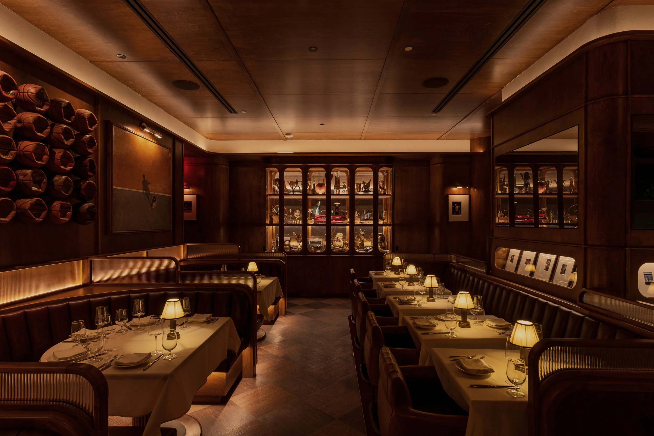 Wide view of the formal dining room with leather banquettes, candlelit tables and illuminated memorabilia cabinets.