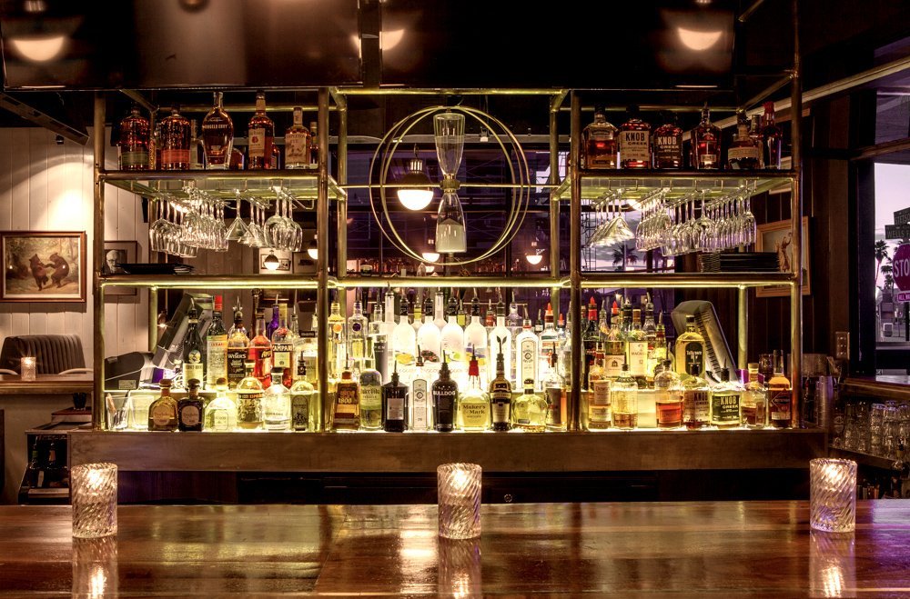 Interior of Goodwood Tavern in Old Town Scottsdale, featuring wood-covered surfaces, dim lighting, comfortable booths and woodland-inspired decorative details.