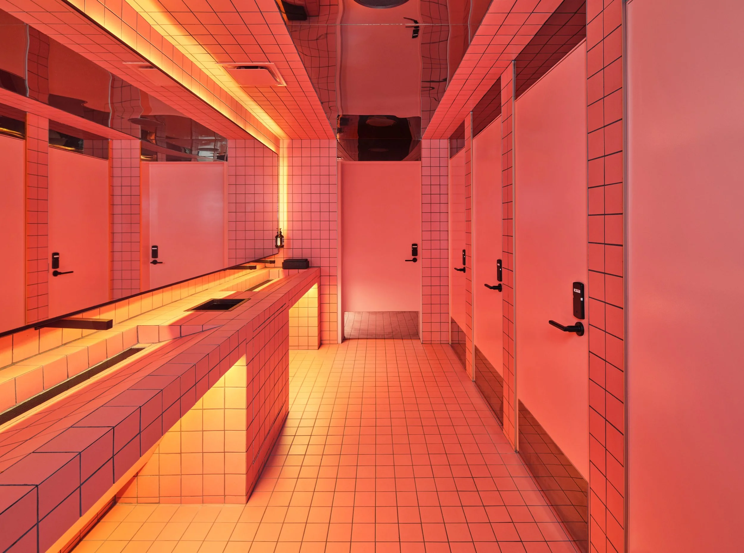 Interior of Powder Room's restroom in downtown Austin, designed by Peter Bowden of PETERMAX Co. with Miami's deco-throwback neon pink grid tile and millwork accent lighting.