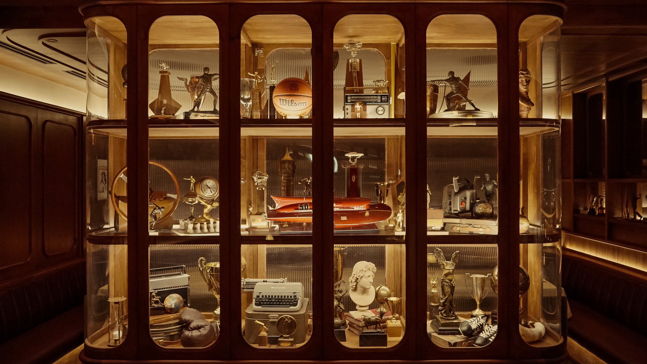 Custom wood-and-glass display cabinets showcase trophies, photographs and vintage sporting objects collected throughout the club.