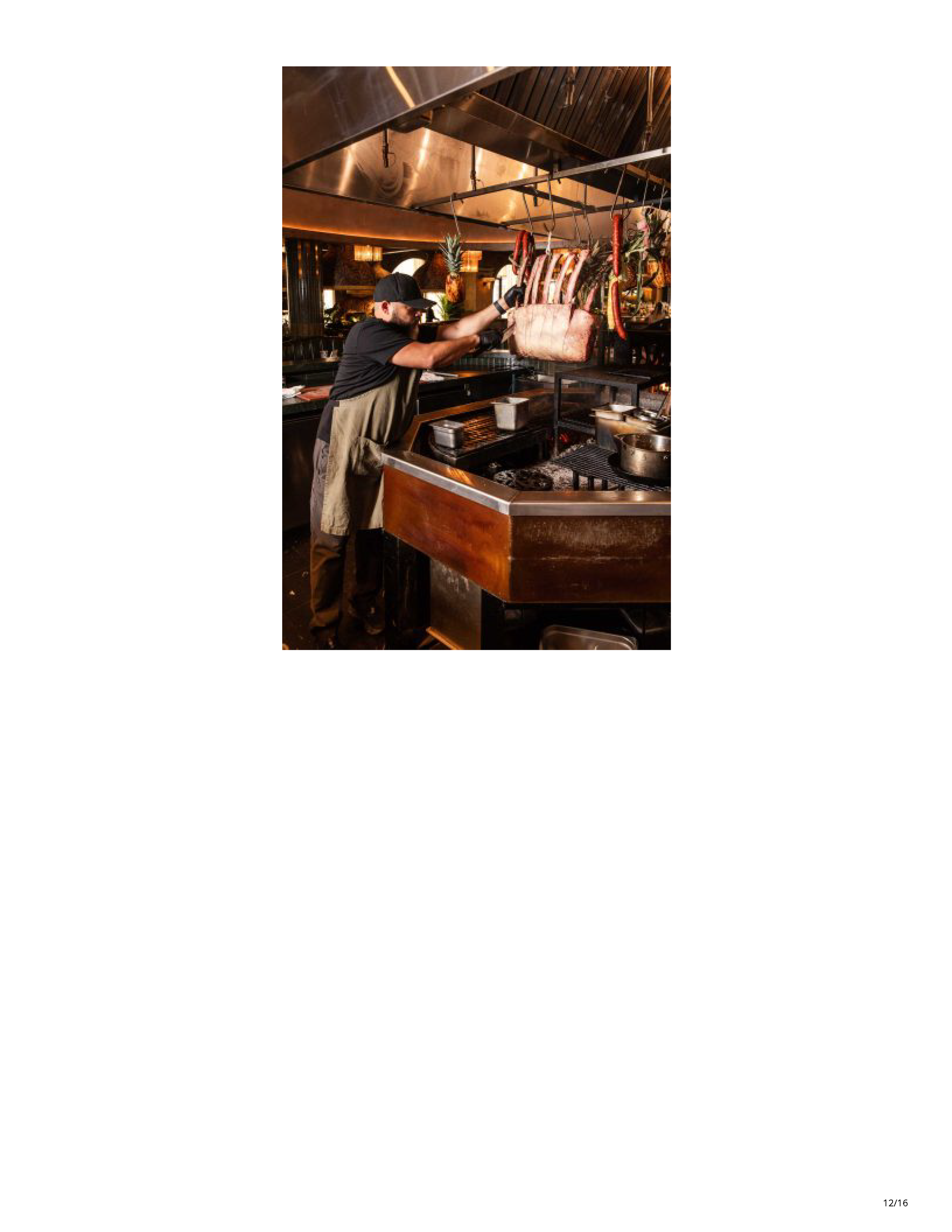 Chef working beside hanging cuts of meat and produce in Filthy Animal’s open kitchen.