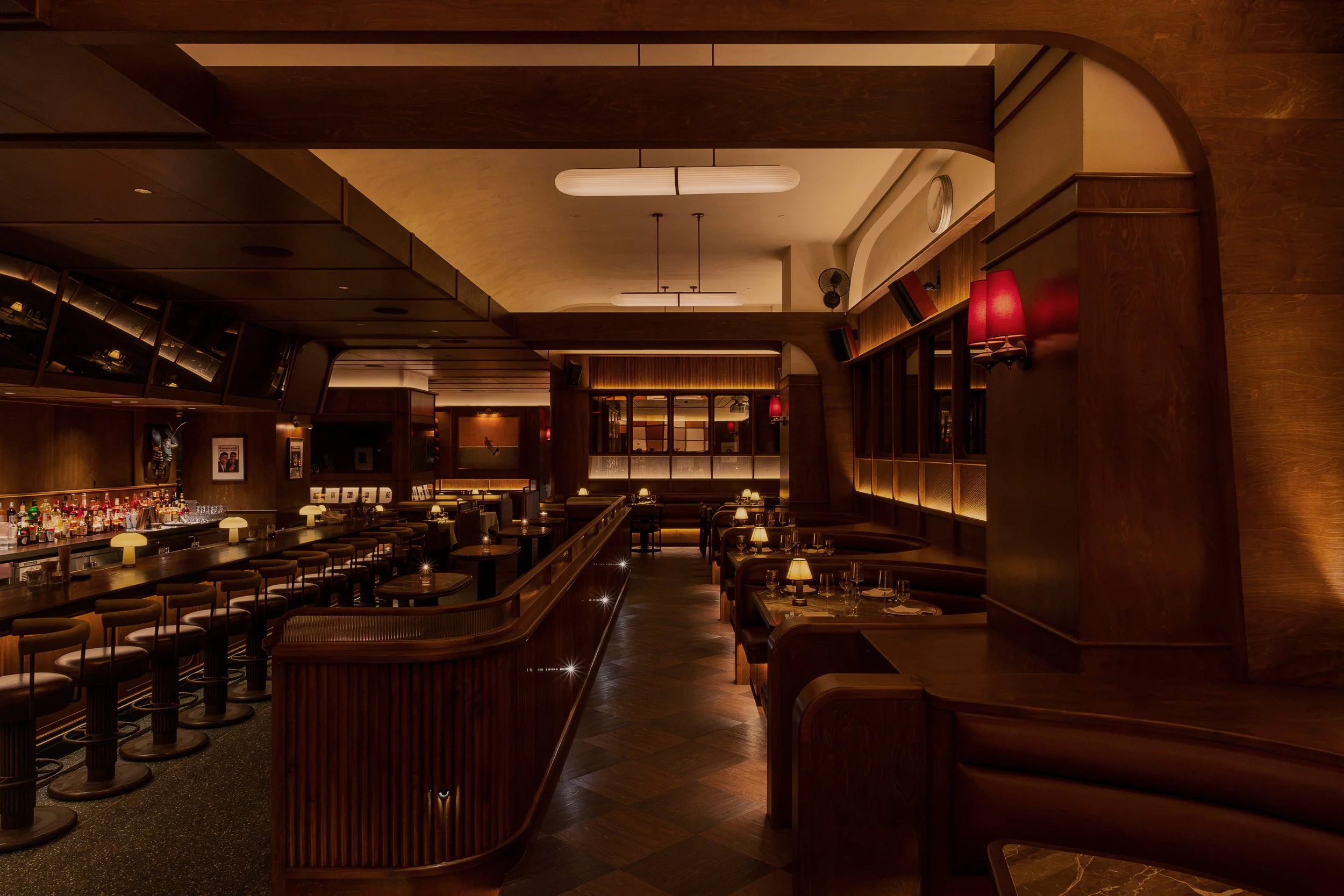 Austin Sports Club’s main dining room pairs dark wood, tailored seating and warm architectural lighting with clear views toward the central bar.