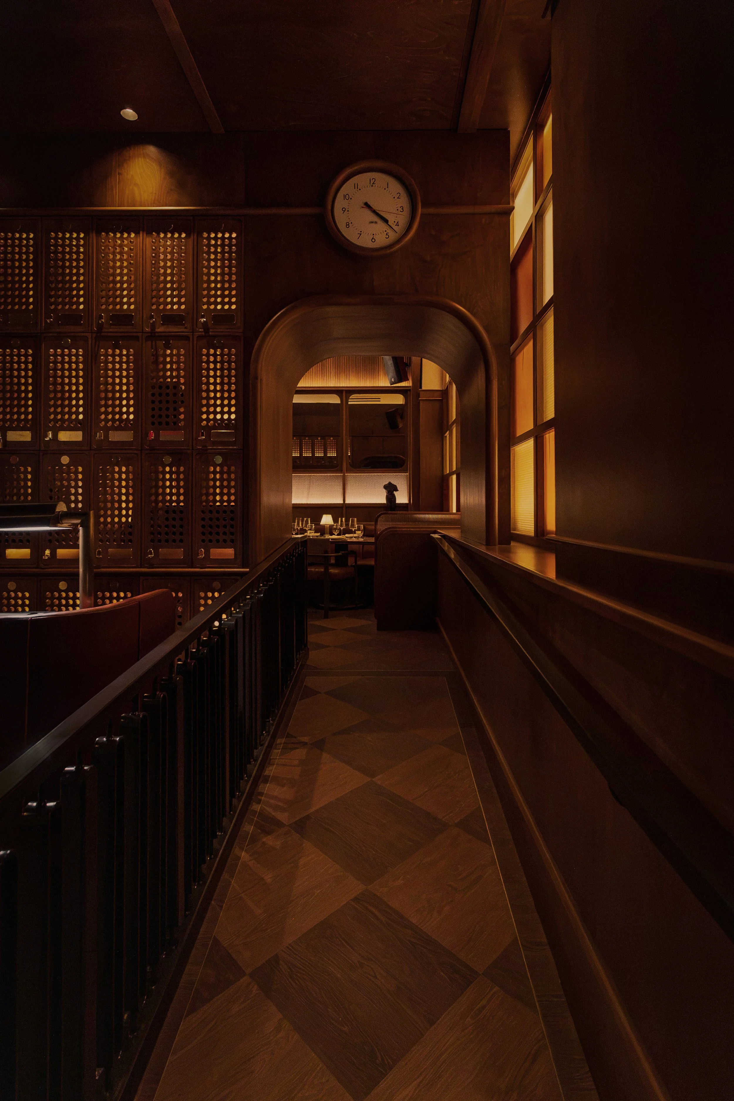 A narrow passage framed by dark wood, bronze detailing and an arched opening leads guests deeper into the club.