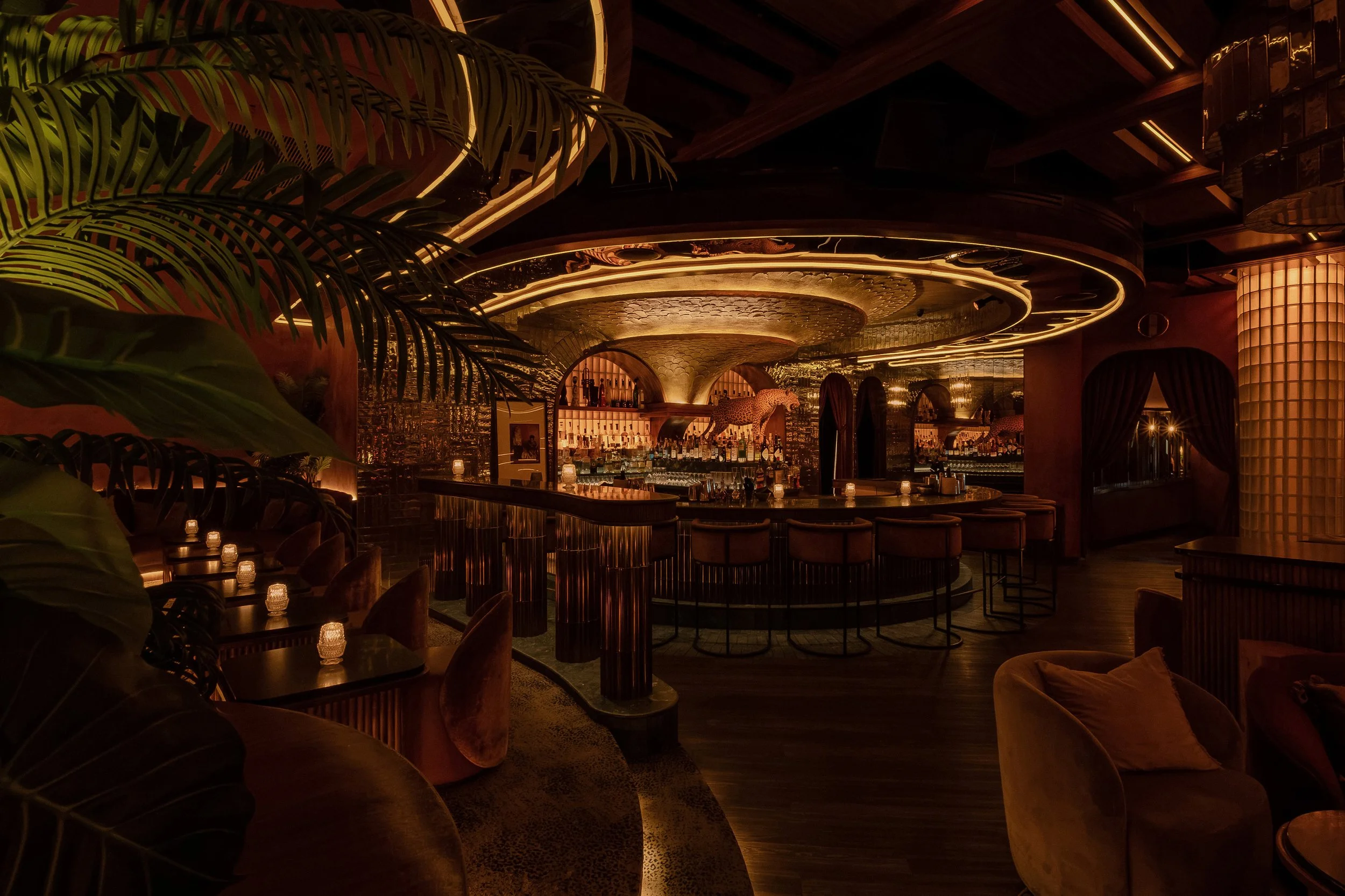 Wide view across Powder Room’s lounge toward the central bar and dramatic concentric illuminated ceiling.