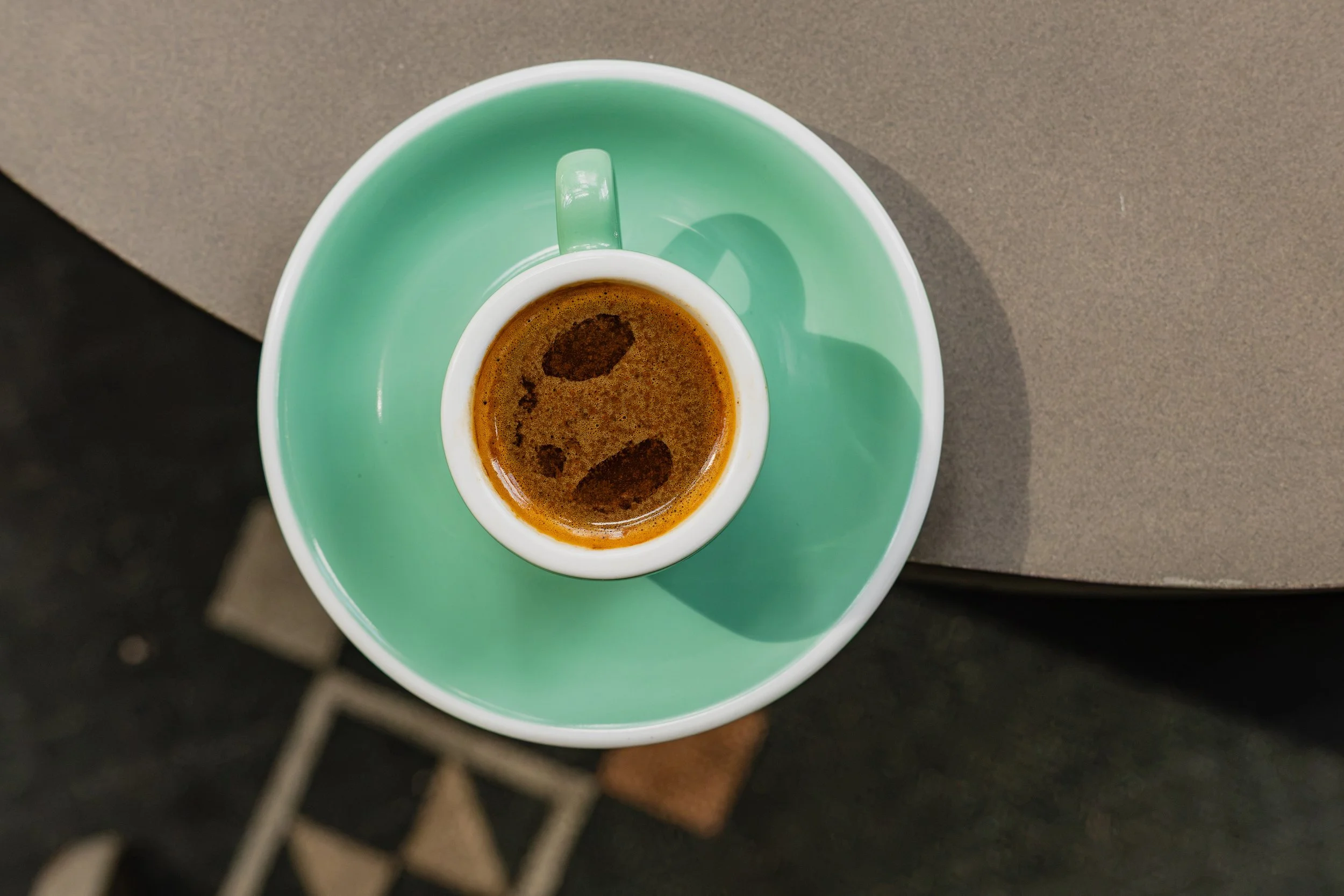 Overhead view of a freshly prepared cafecito in a seafoam green cup and saucer at Manny’s in downtown Austin.