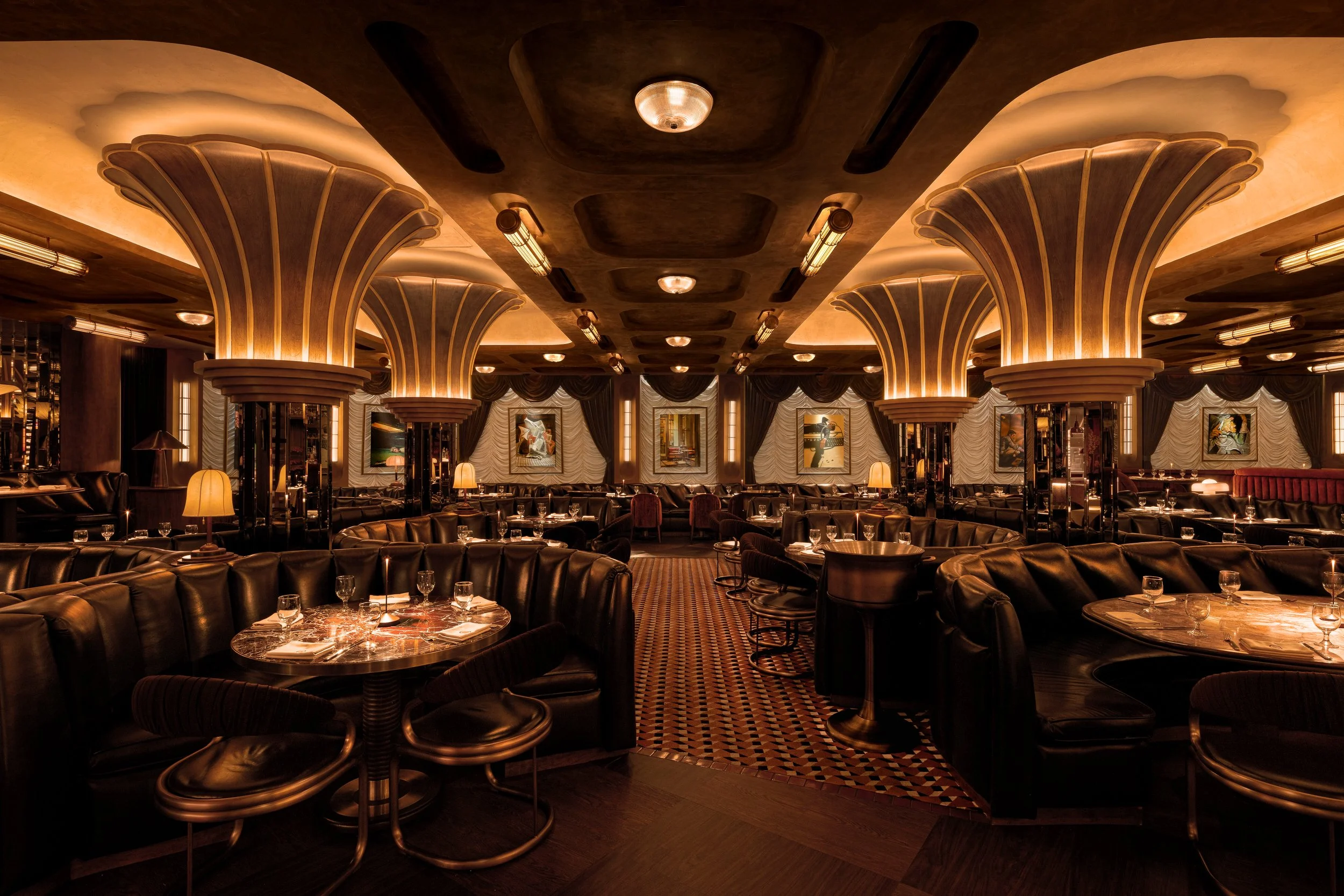 Cleaverman steakhouse dining room in Downtown Phoenix, designed by Peter Bowden and PETERMAX Co., featuring illuminated fluted wood columns, dark leather banquettes, marble-topped tables, arched detailing, and warm amber lighting.