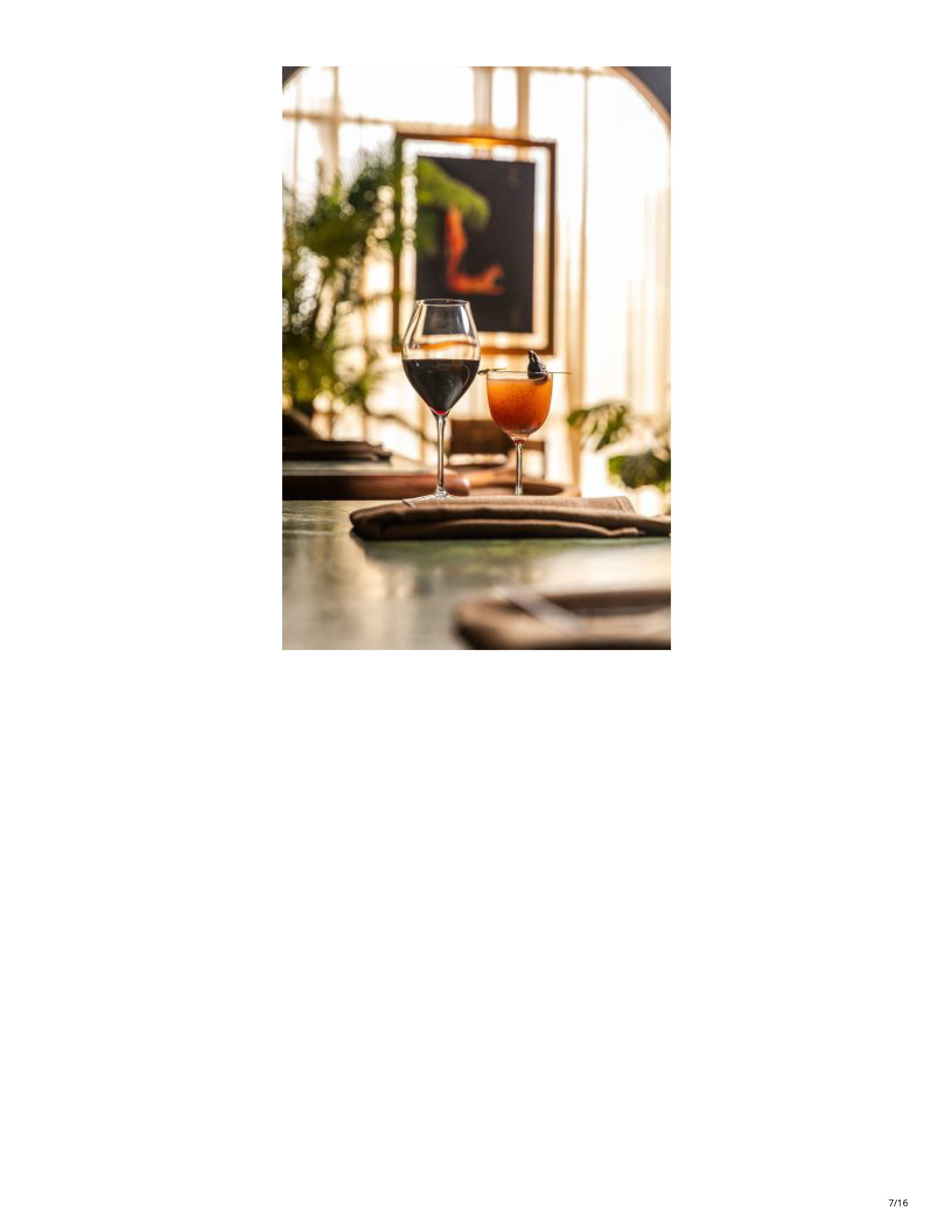 Wine and a cocktail presented inside Filthy Animal against a bright arched window and tropical planting.
