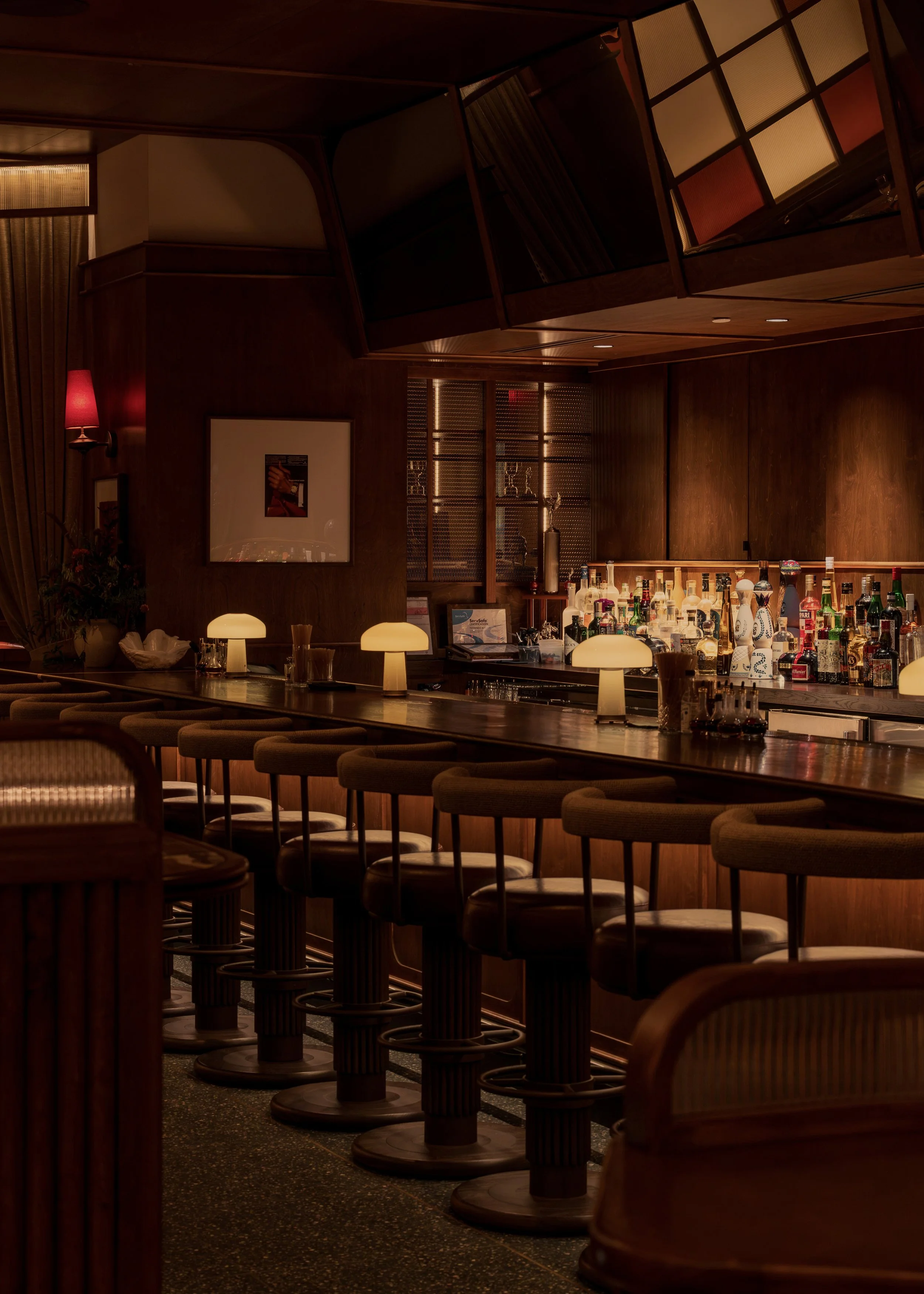 Austin Sports Club’s bar pairs leather seating, intimate table lamps and framed art with a dramatic metal-screened staircase beyond.
