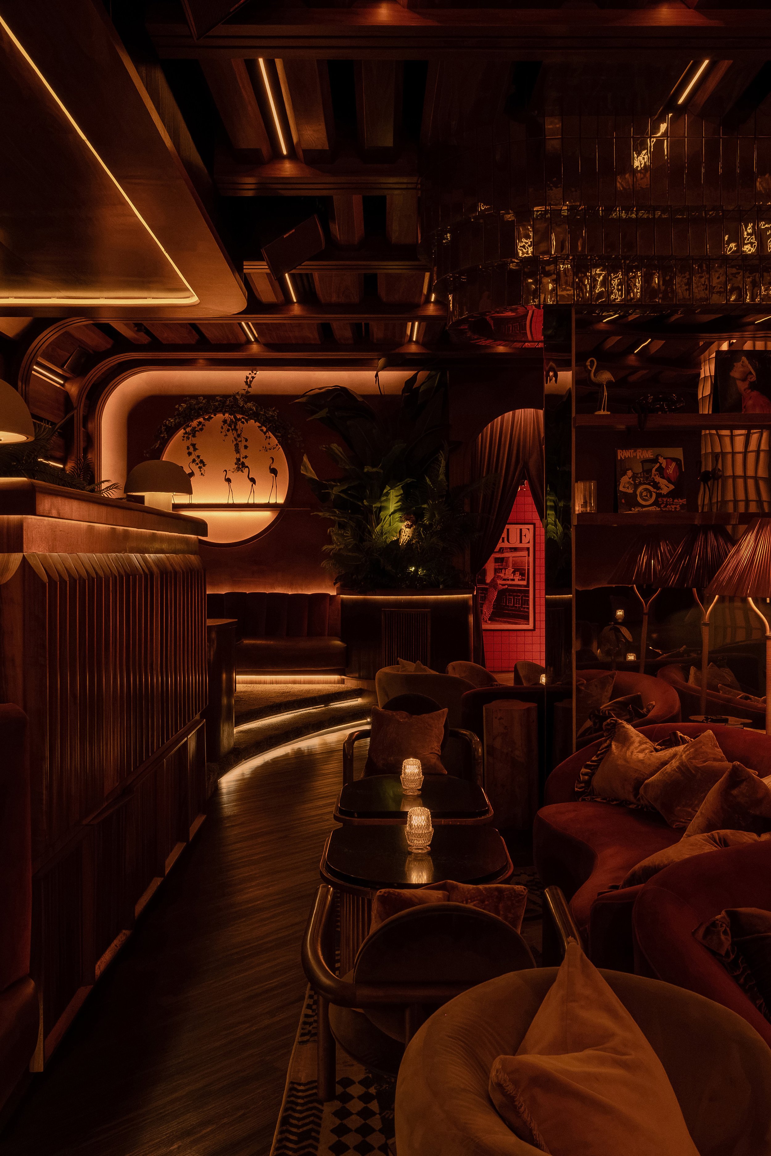 Intimate seating nook at Powder Room in Austin with curved wood paneling, amber lighting, framed artwork and plush lounge chairs.