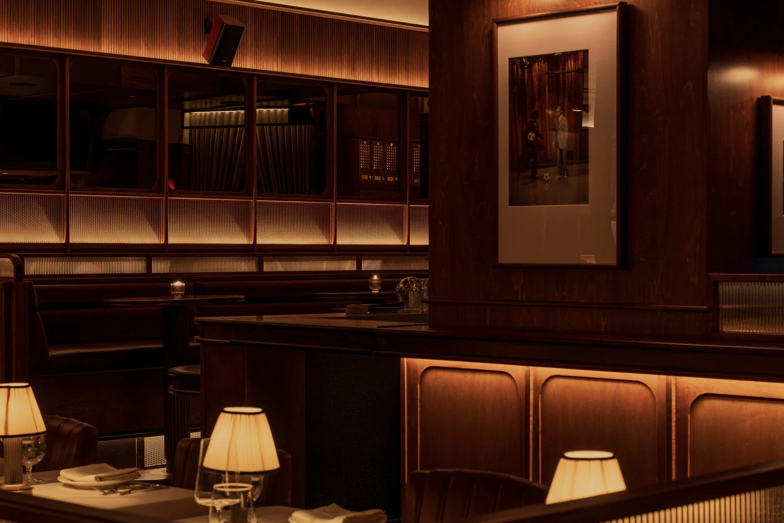 An intimate booth at Austin Sports Club features leather seating, shaded table lamps and decorative glass-and-metal screens.