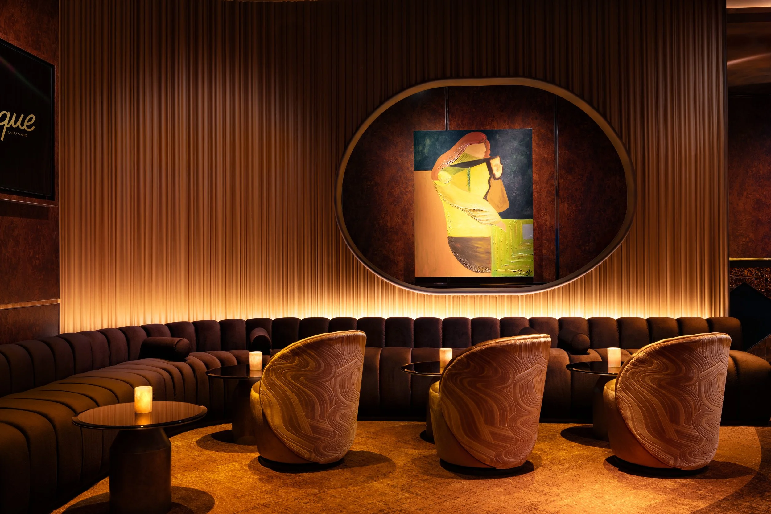 Redesigned interior of Clique Bar & Lounge at The Cosmopolitan of Las Vegas, featuring a warm, gilded palette, intimate lounge seating and a glowing central bar.