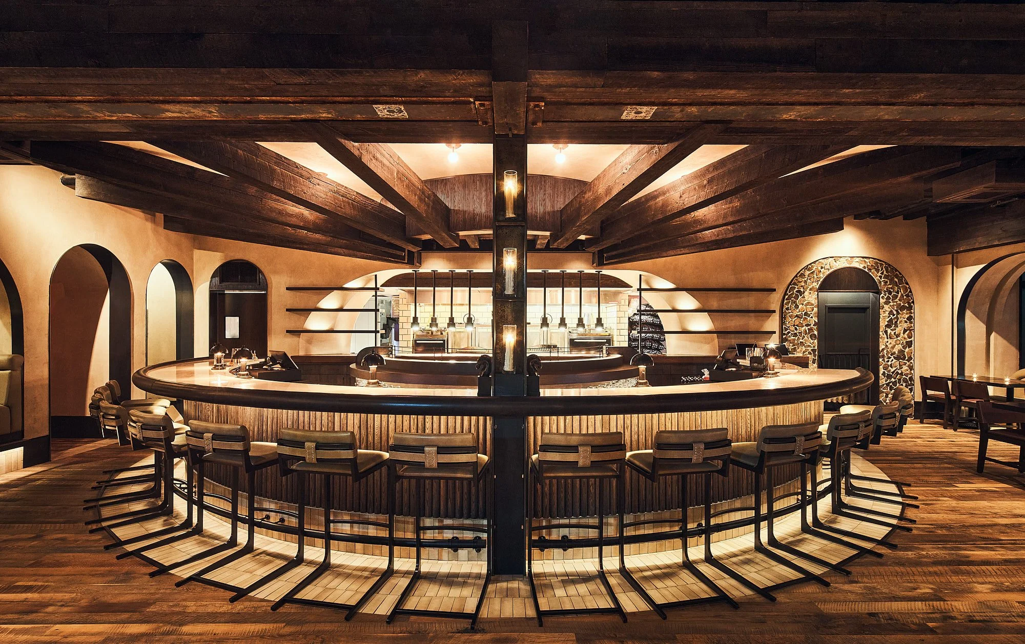 dLeña modern Mexican restaurant in Washington, DC, featuring a circular wood-paneled bar, warm lighting, arched openings, leather seating, and rustic architectural details.