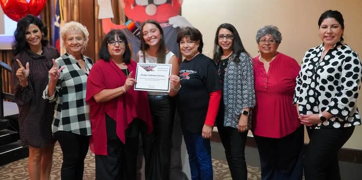 Two women smiling, one holding a certificate, in an indoor setting.