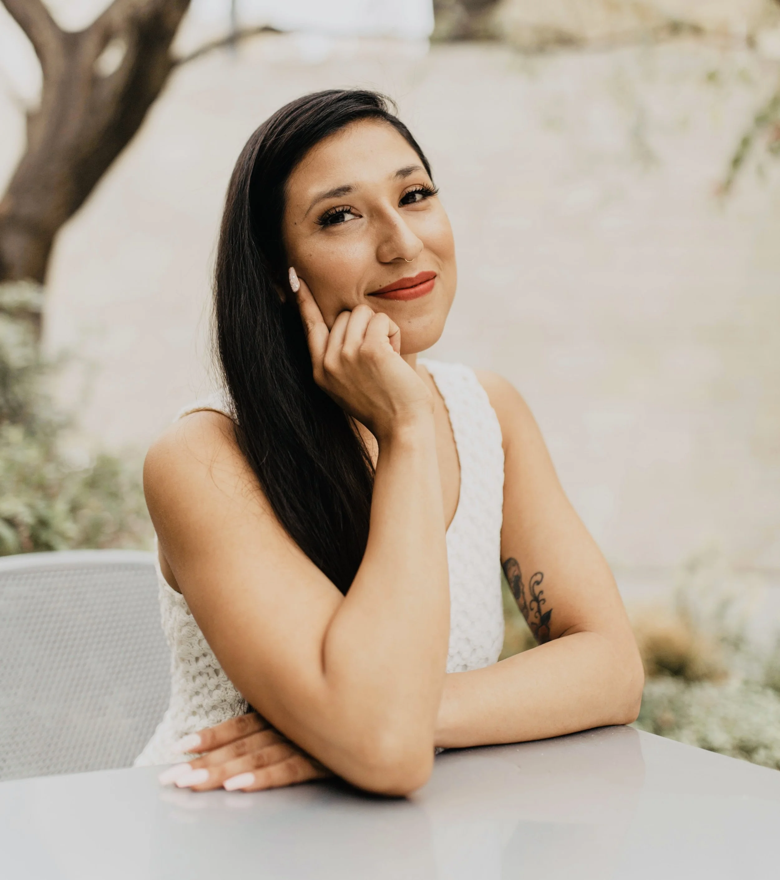 Warm and inviting therapist with long dark hair, in an outdoor portrait