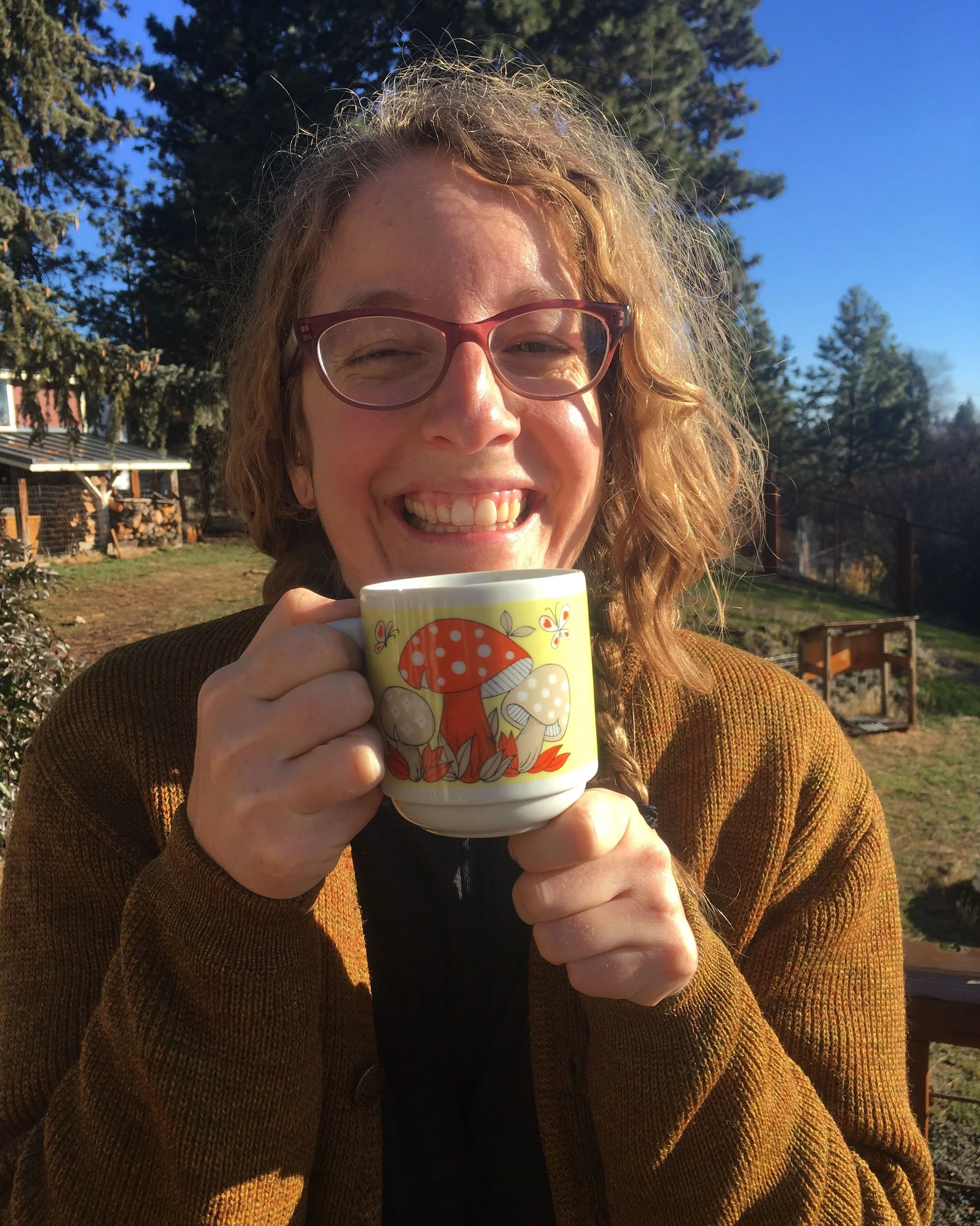 Close up picture of Meghan grinning while holding a vintage mushroom mug