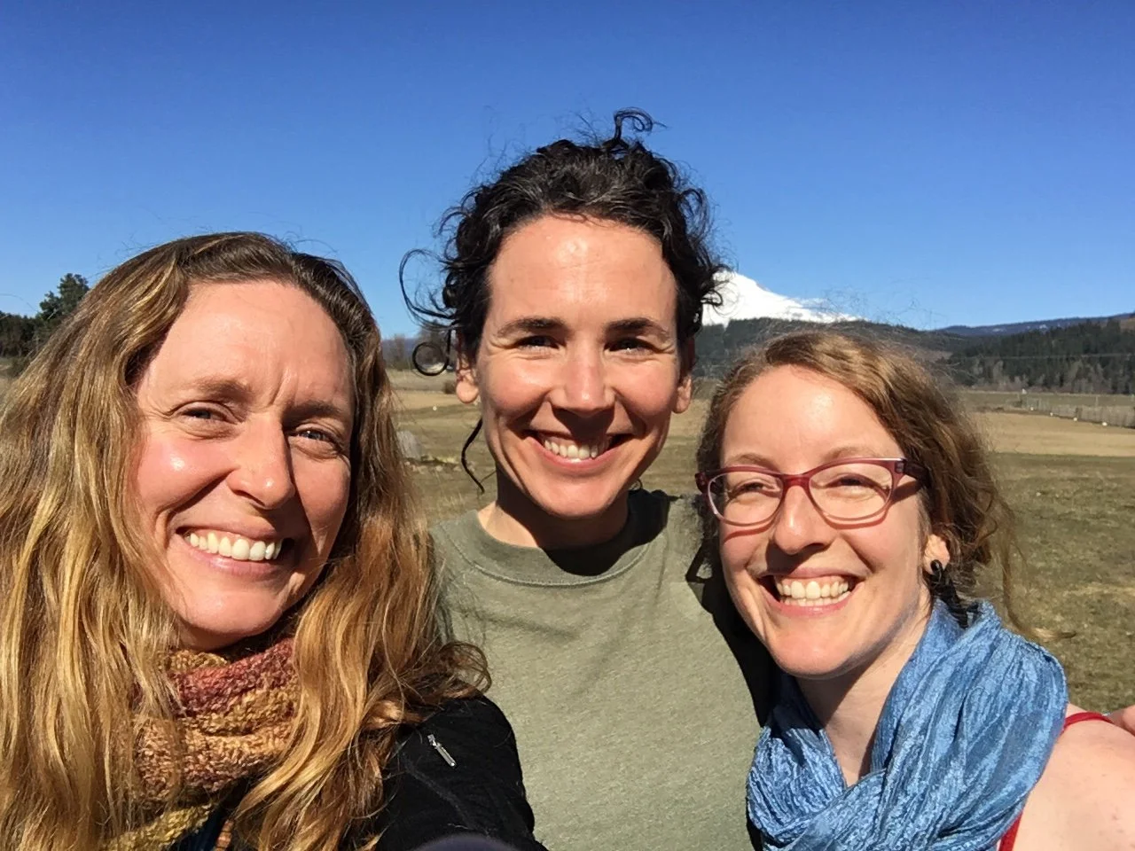 Caverly, Suniti, and Meghan smile at the camera with Mt Adams in the background