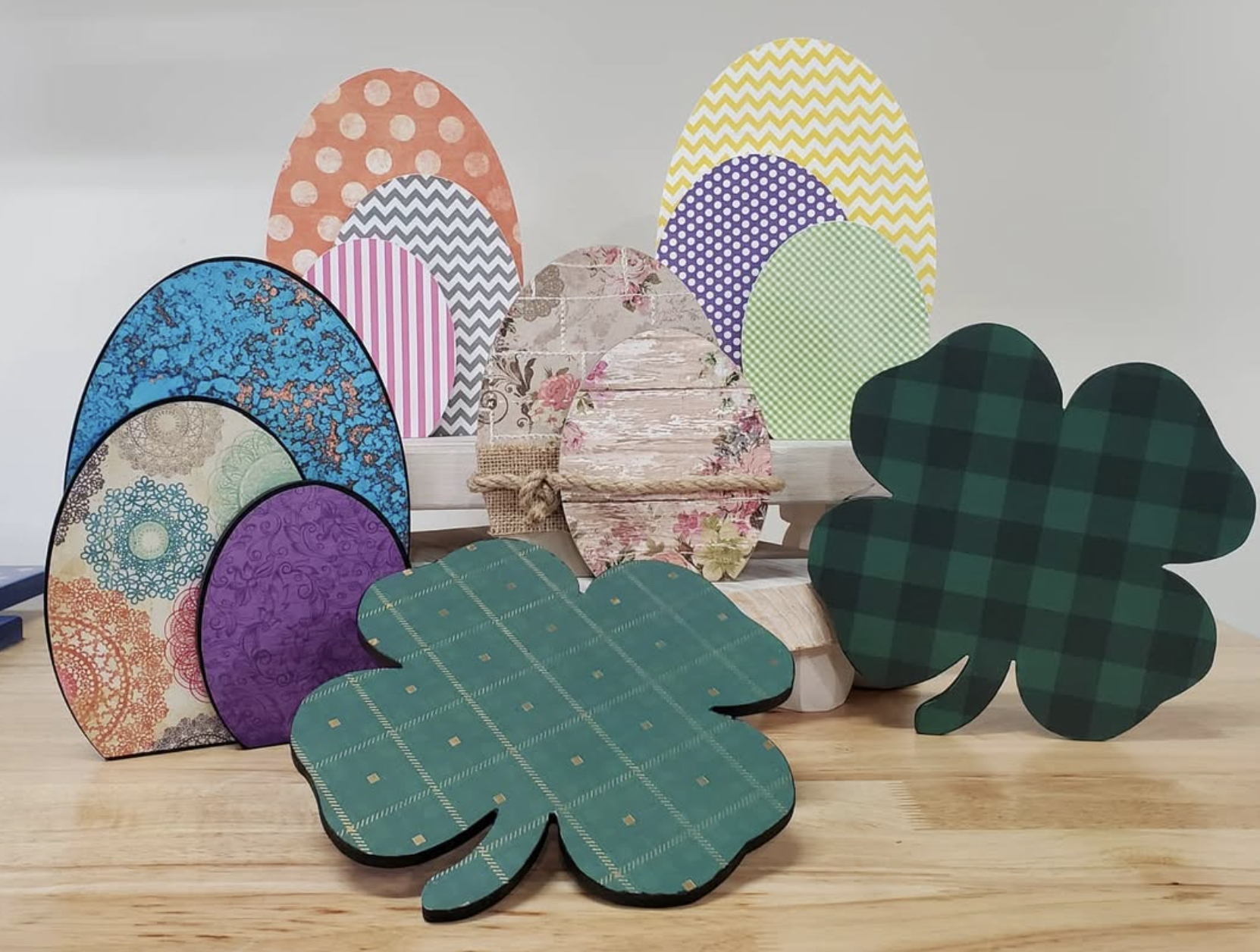 Colorful patterned paper cutouts of Easter eggs and shamrocks arranged on a wooden surface.
