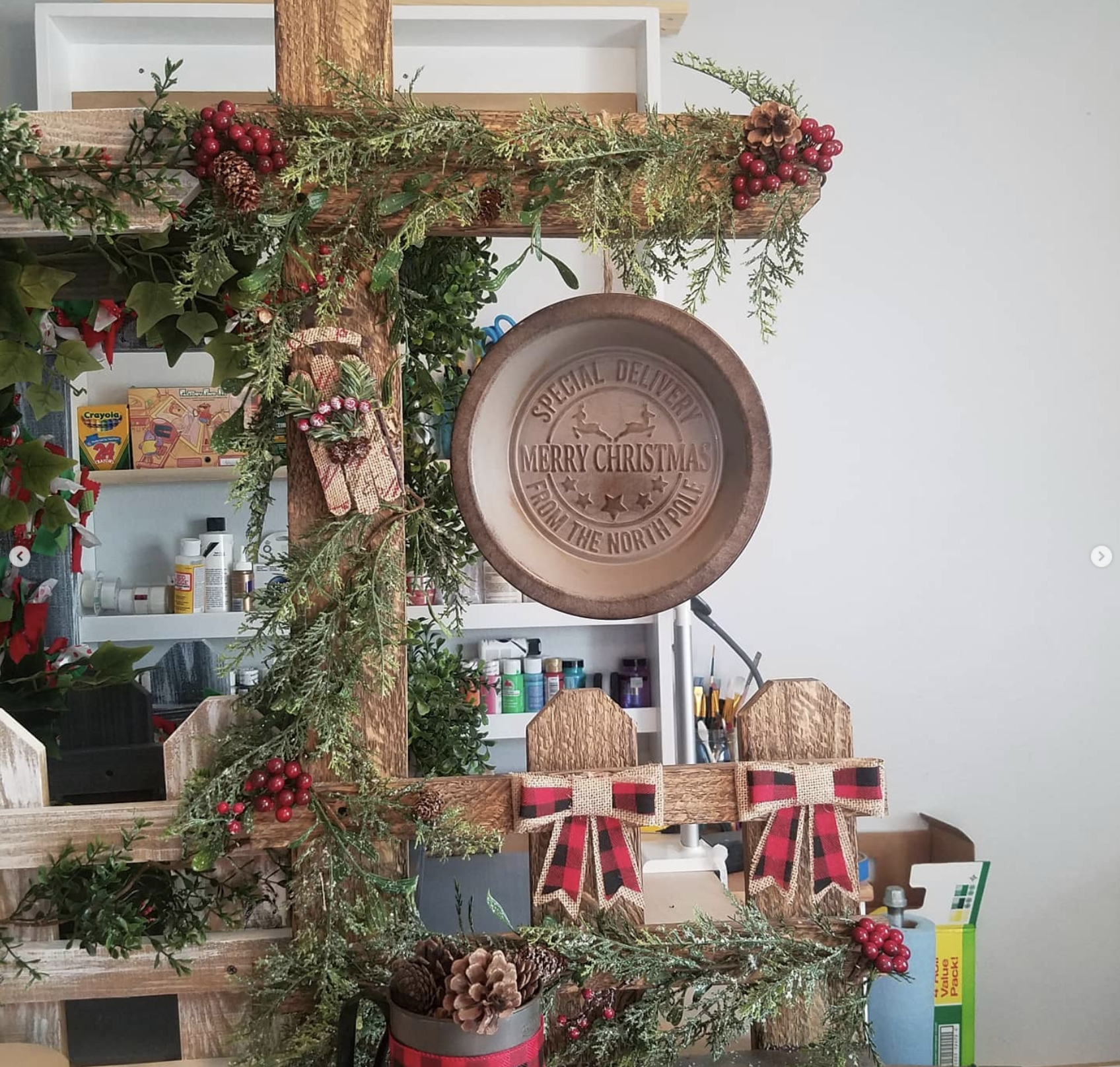 Decorated Christmas display with greenery, berries, pinecones, and a wooden sign that reads 'Special Delivery Merry Christmas from the North Pole' in a festive interior setting.