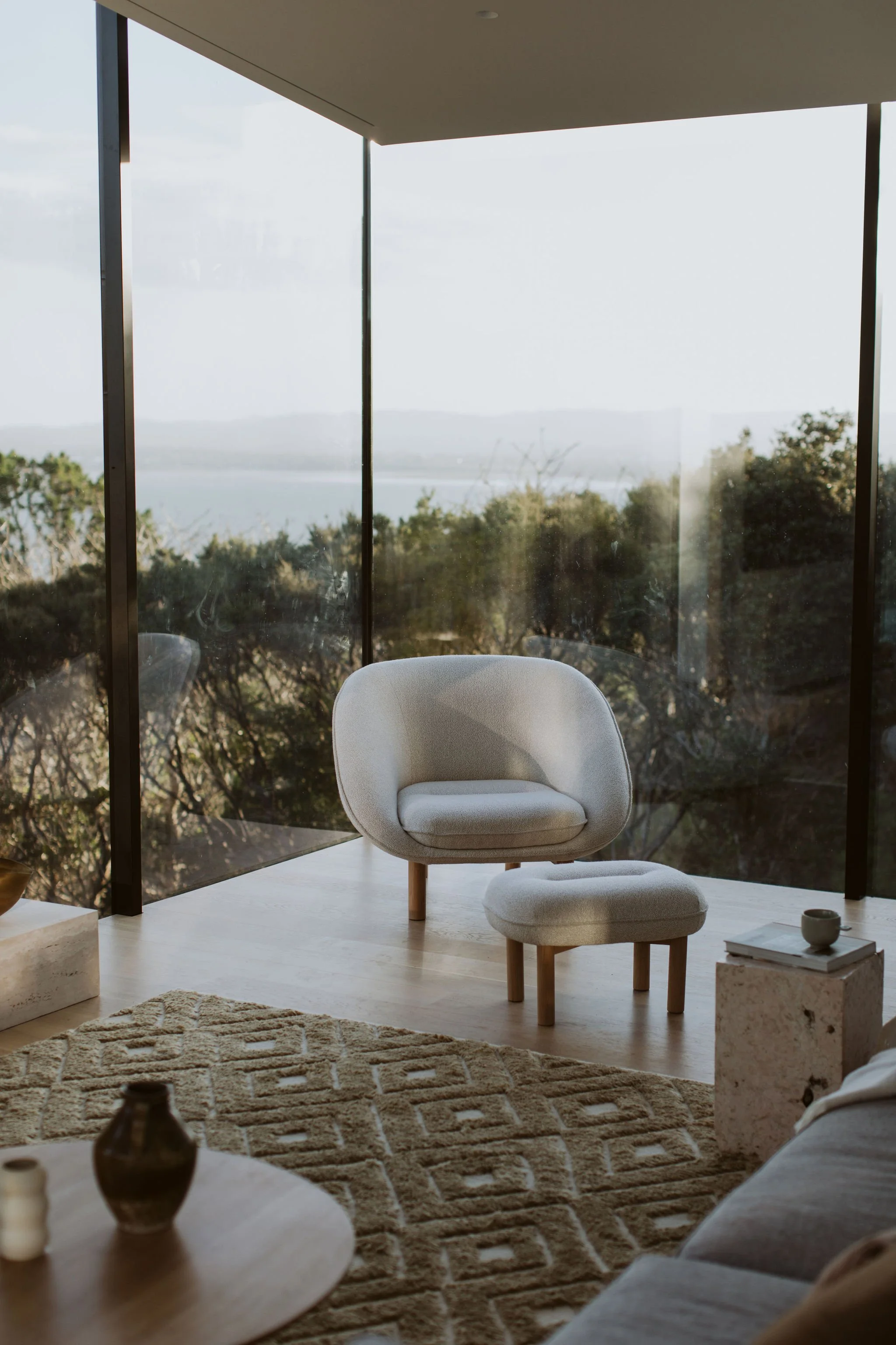 Island Bay House Living Room designed by Walls Studio. Floor to ceiling glass in a corner room that looks over New Zealand native bush.