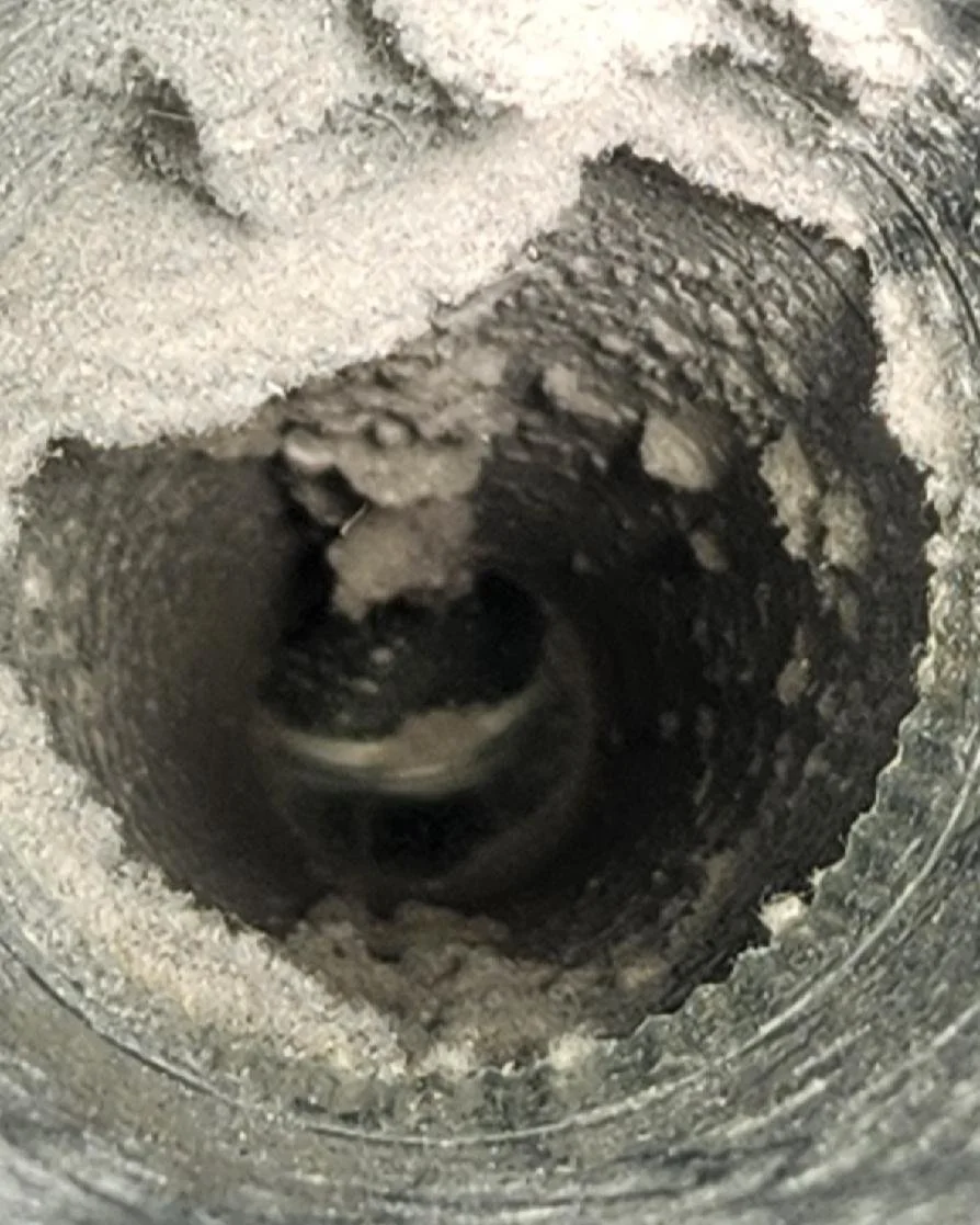 Close-up of a cylindrical metal part used for dryer vents coated with dirt and lint buildup from not cleaning it regularly.