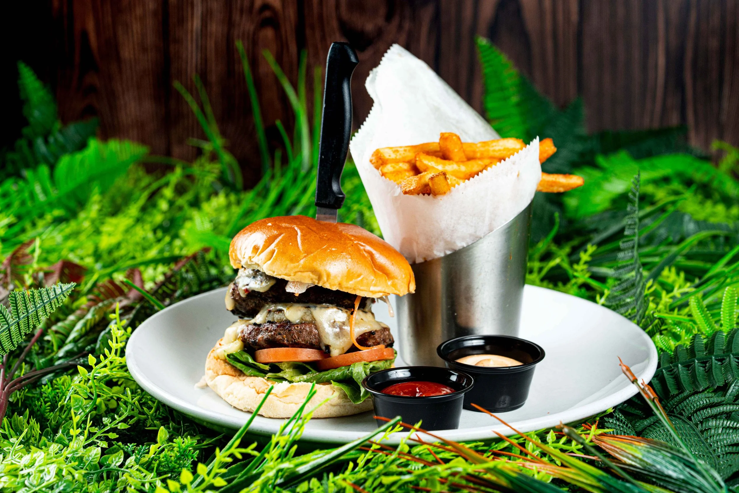 Burger topped with Pepperjack Cheese, Grilled Pineapple, Sweet Chili Sauce, Lettuce, Tomatoes, and Escovitch Slaw.