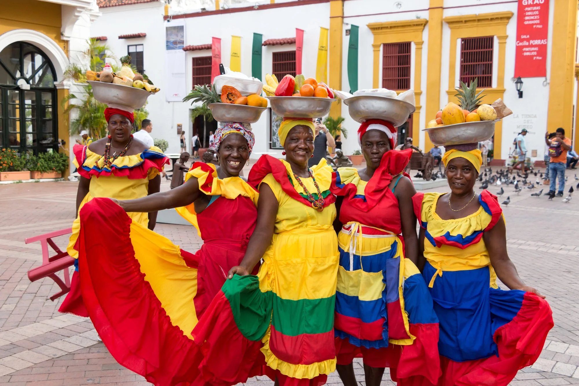 Caribbean women dressed in traditional outfit selling fruits in the market.