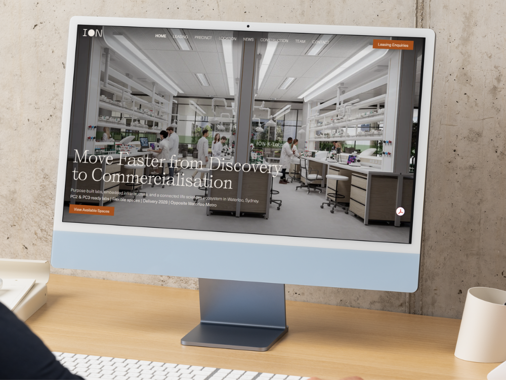 Computer screen showing a website for a scientific laboratory or research facility, with a view of a modern lab with scientists working at their stations.