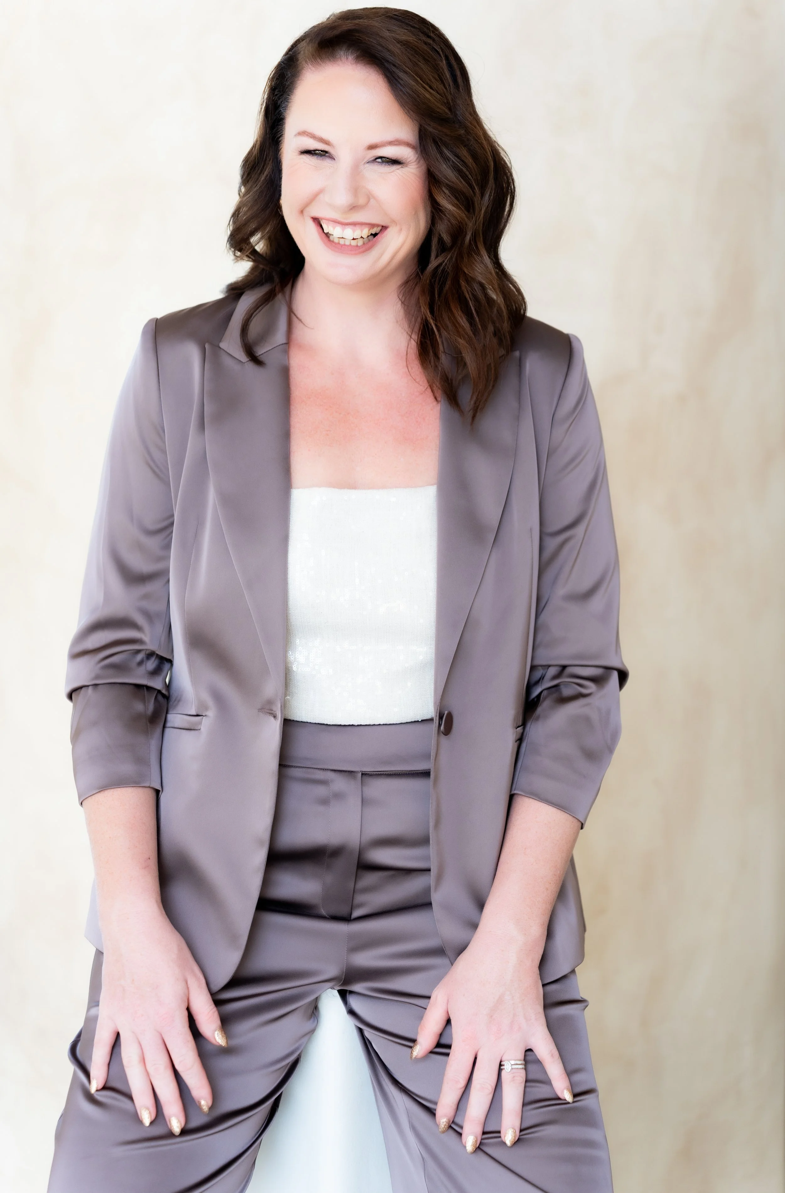 Woman with brown hair in a gray suit, smiling and looking at the camera.