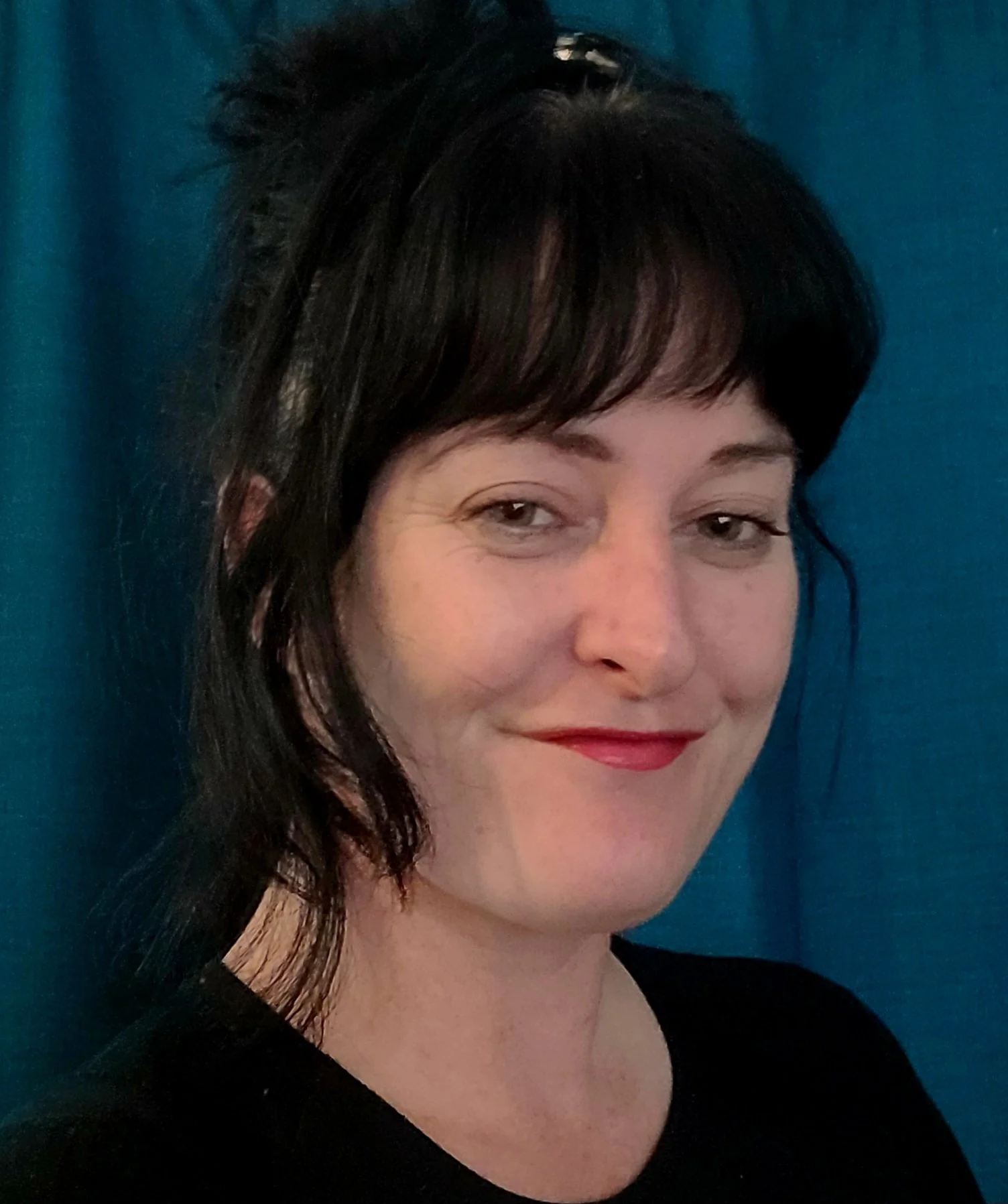 A close-up of a smiling white woman with black hair