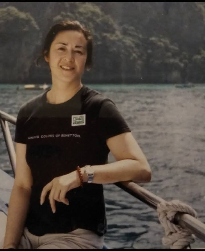 A smiling asian lady standing on a boat wearing a black t-shirt