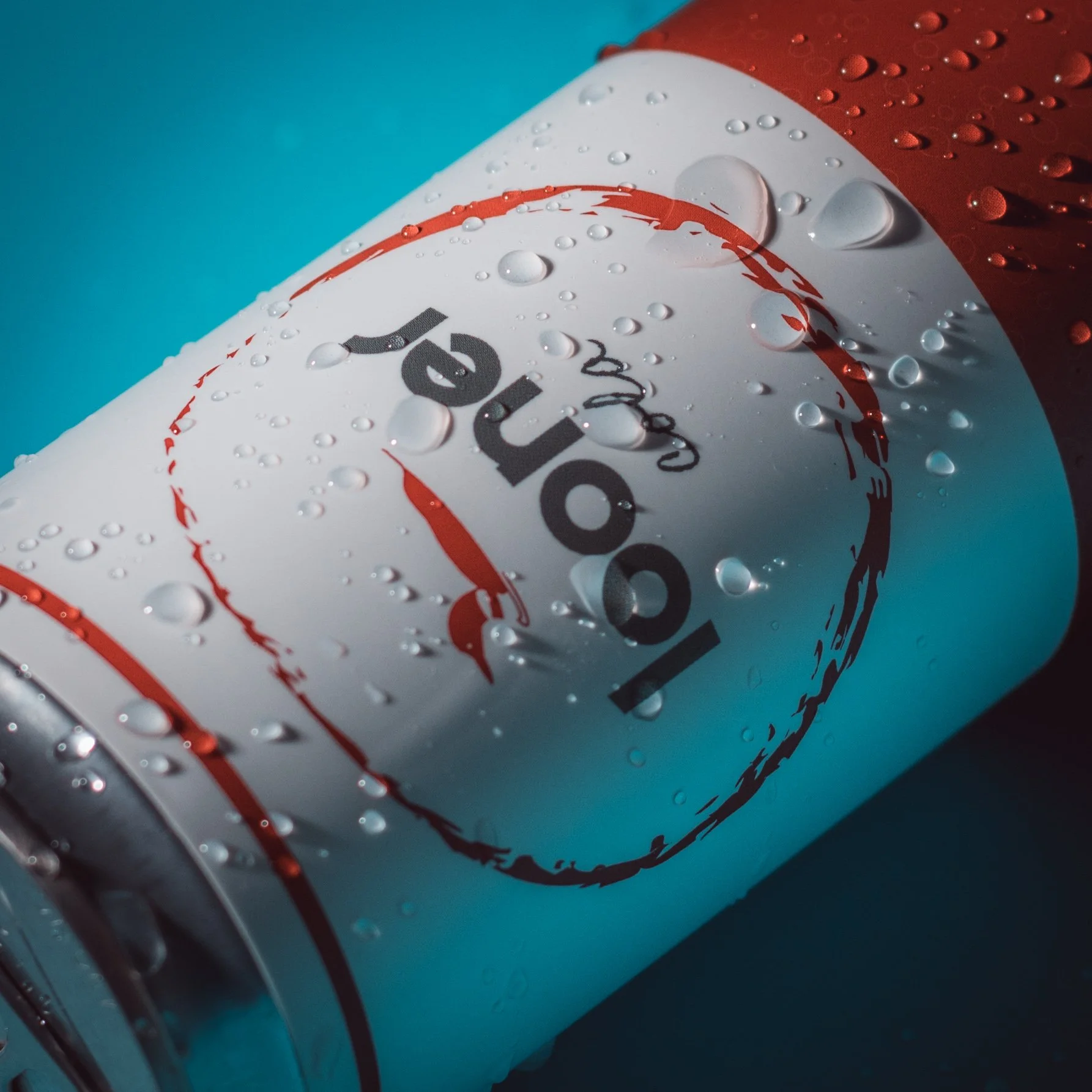 A close-up of a cooled can of Coca-Cola with condensation droplets on its surface, lying on a blue background.