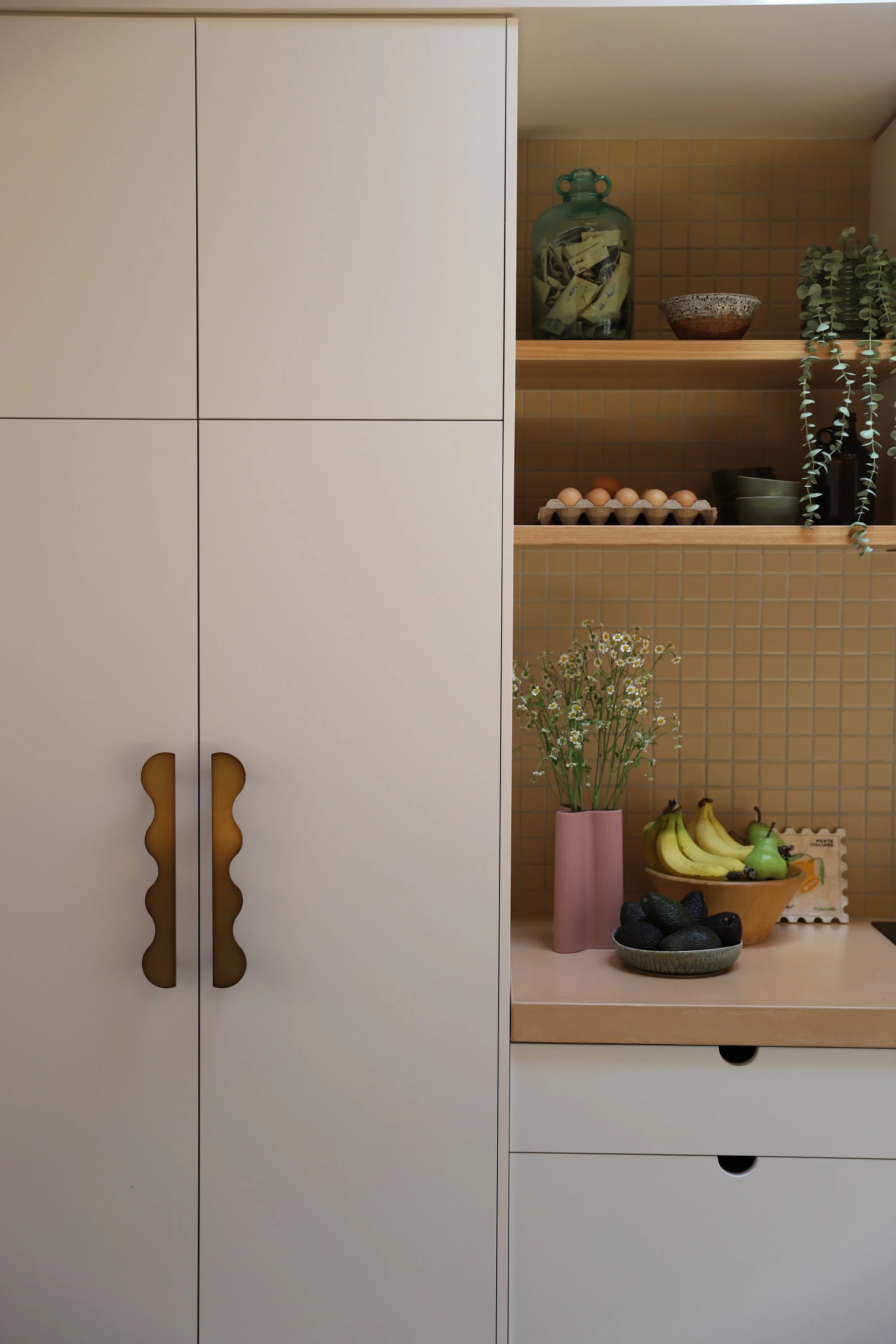 Close up of white kitchen pantry cabinetry and a yellow mosaic backsplash