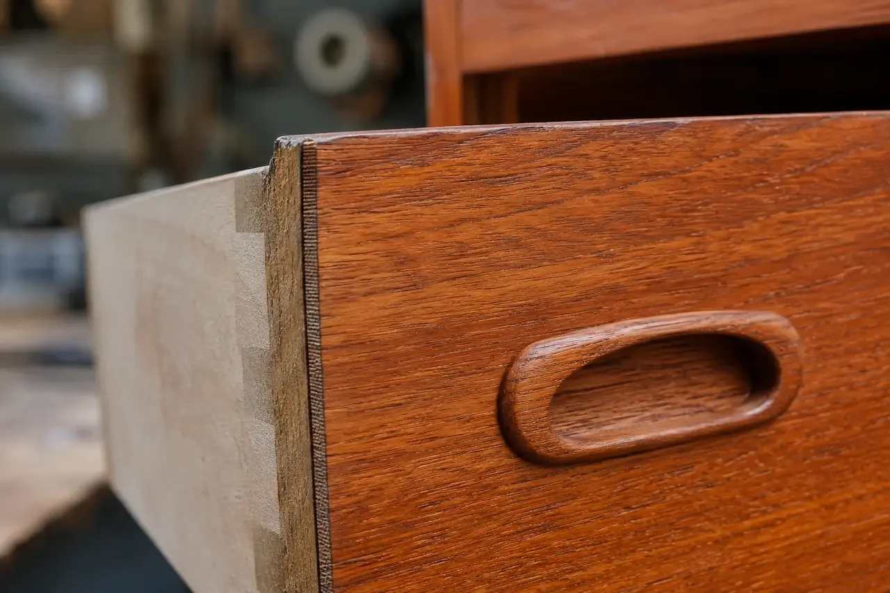Teak veneer edge on a G Plan drawer front showing the veneer line against the core
