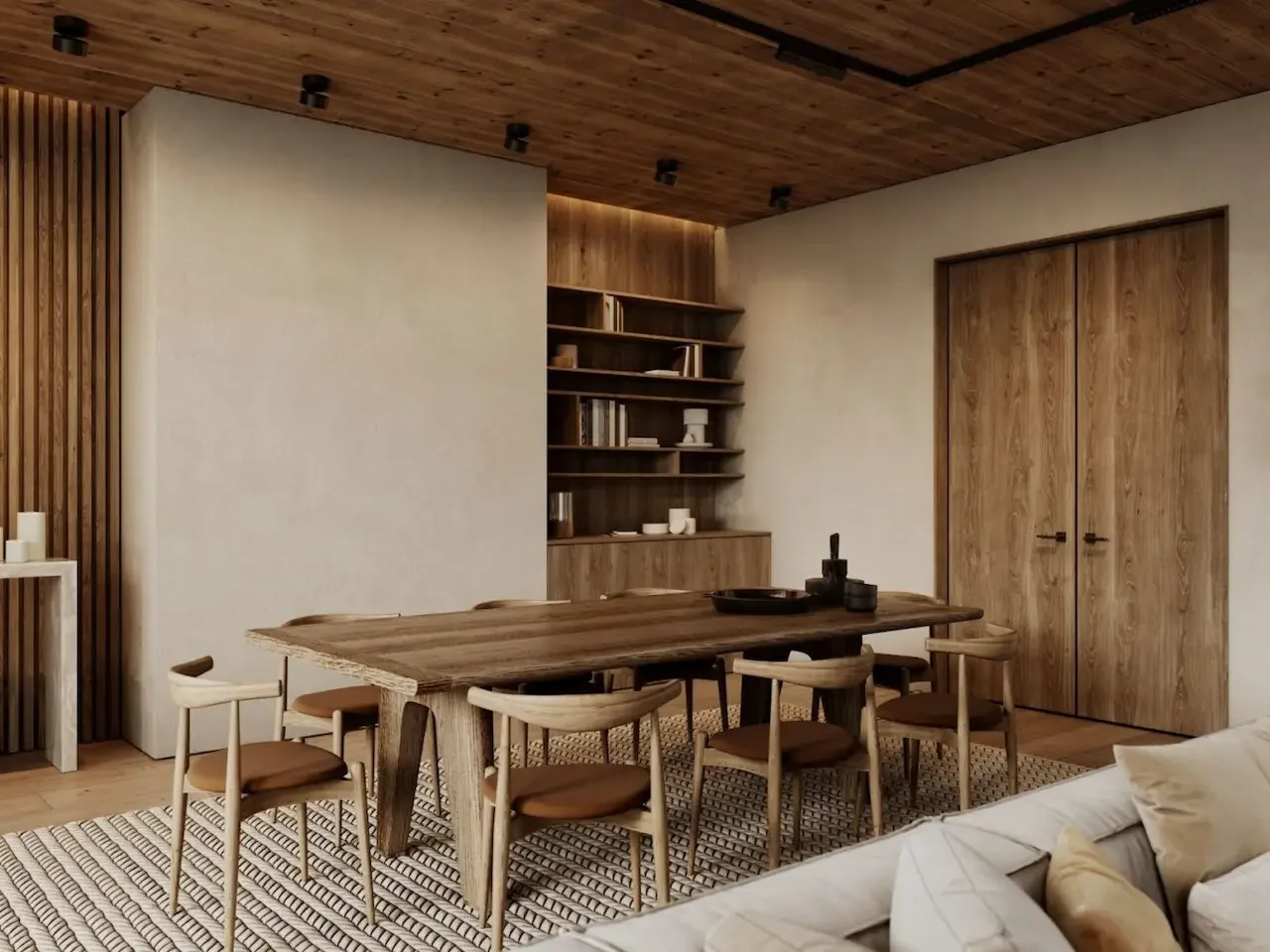 A dining room with wooden furniture, including a table and chairs, a built-in bookcase, wooden ceiling, and a patterned rug.
