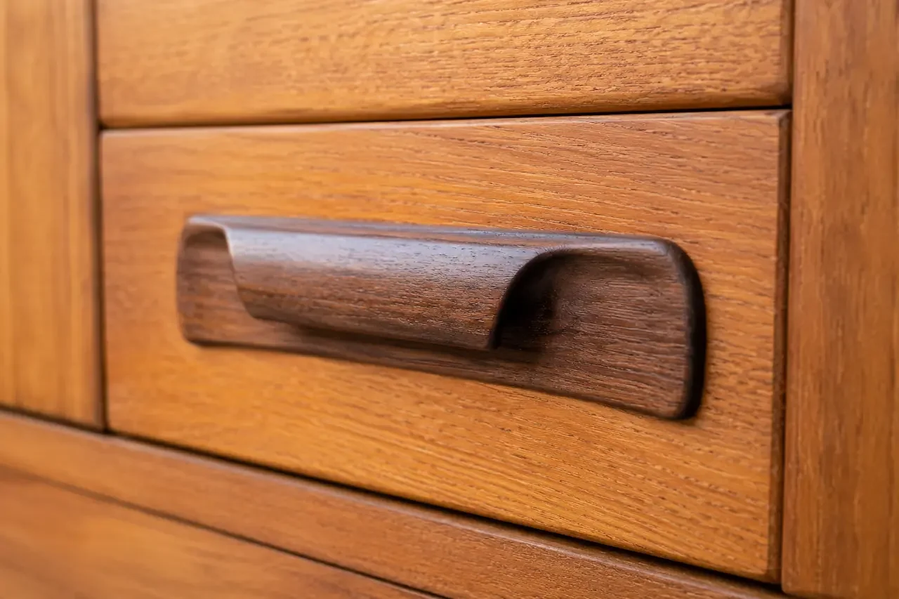 Close detail of an afrormosia handle against teak on a G Plan Fresco sideboard