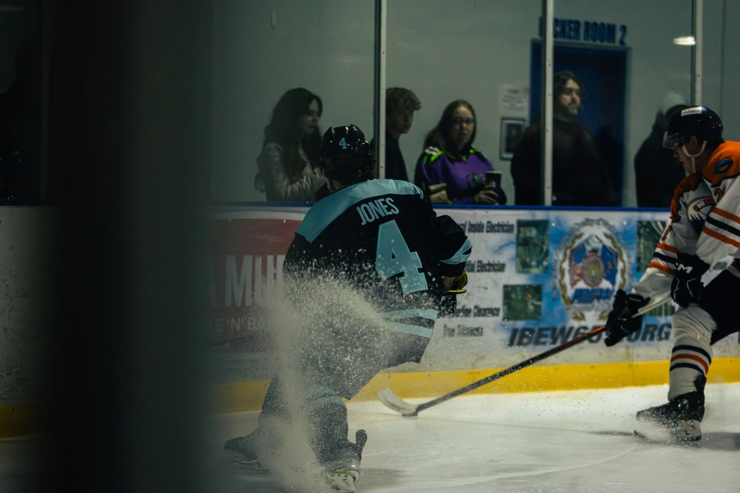 Hockey game in progress at an ice rink with players and spectators watching.