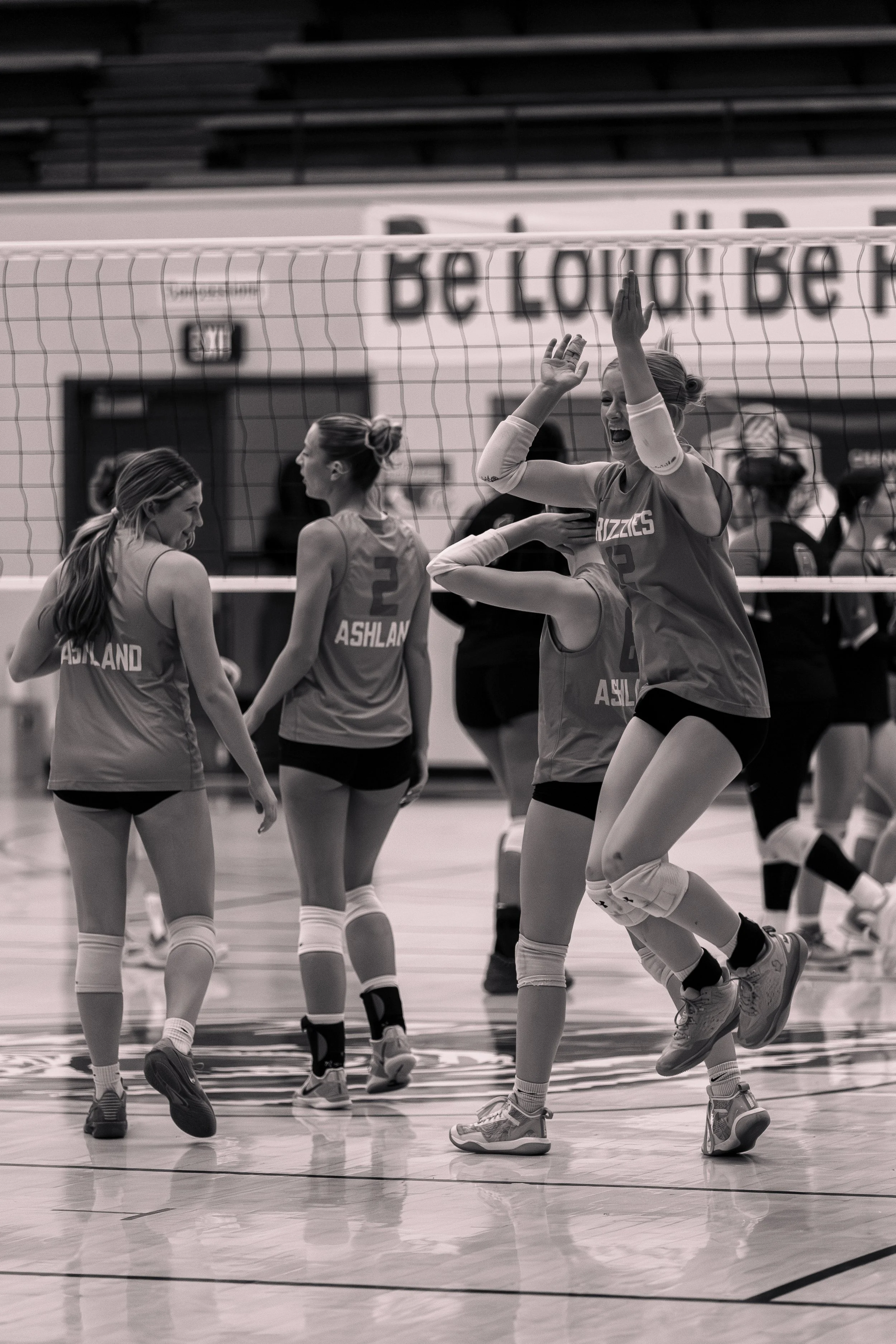 Group of female volleyball players celebrating on the court during a game.
